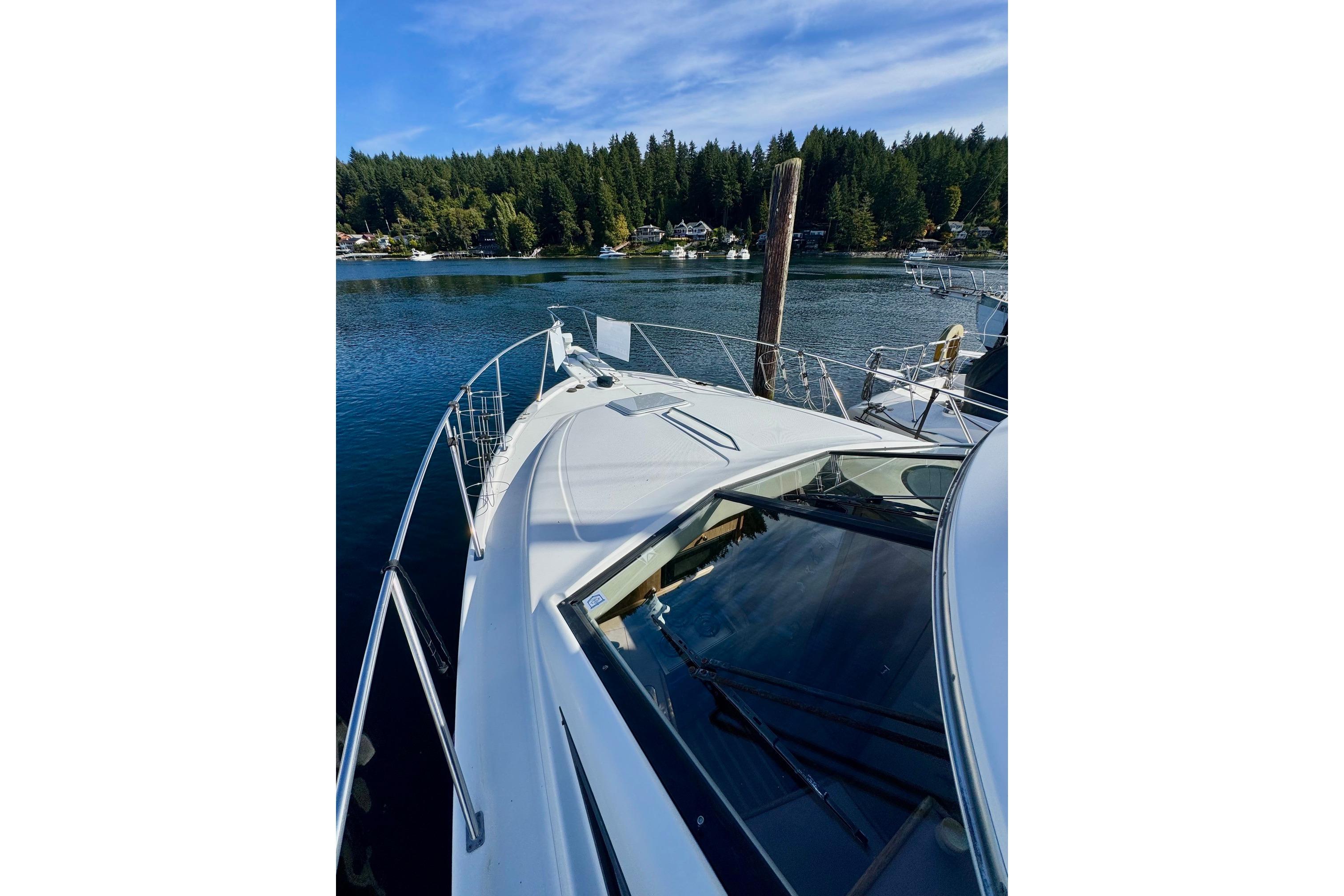 1998 Bayliner 3388 Command Bridge Motoryacht on serene lake with forested shoreline.