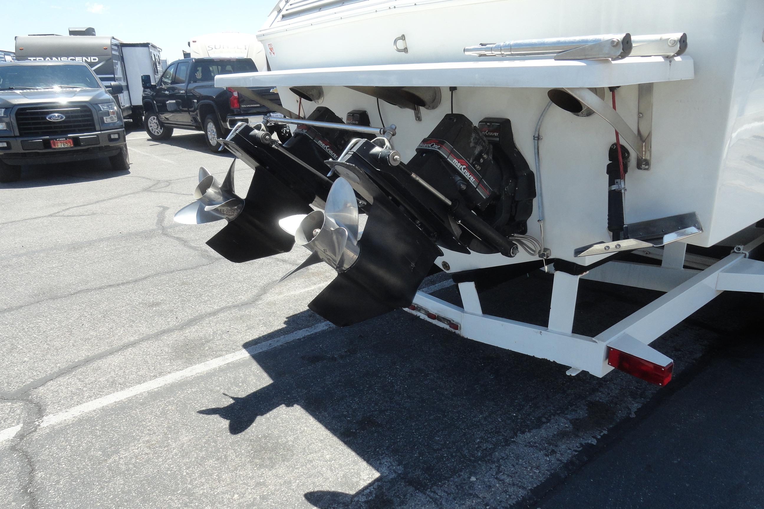 1988 Wellcraft 34 Scarab boat with dual propellers on a trailer in a parking lot.
