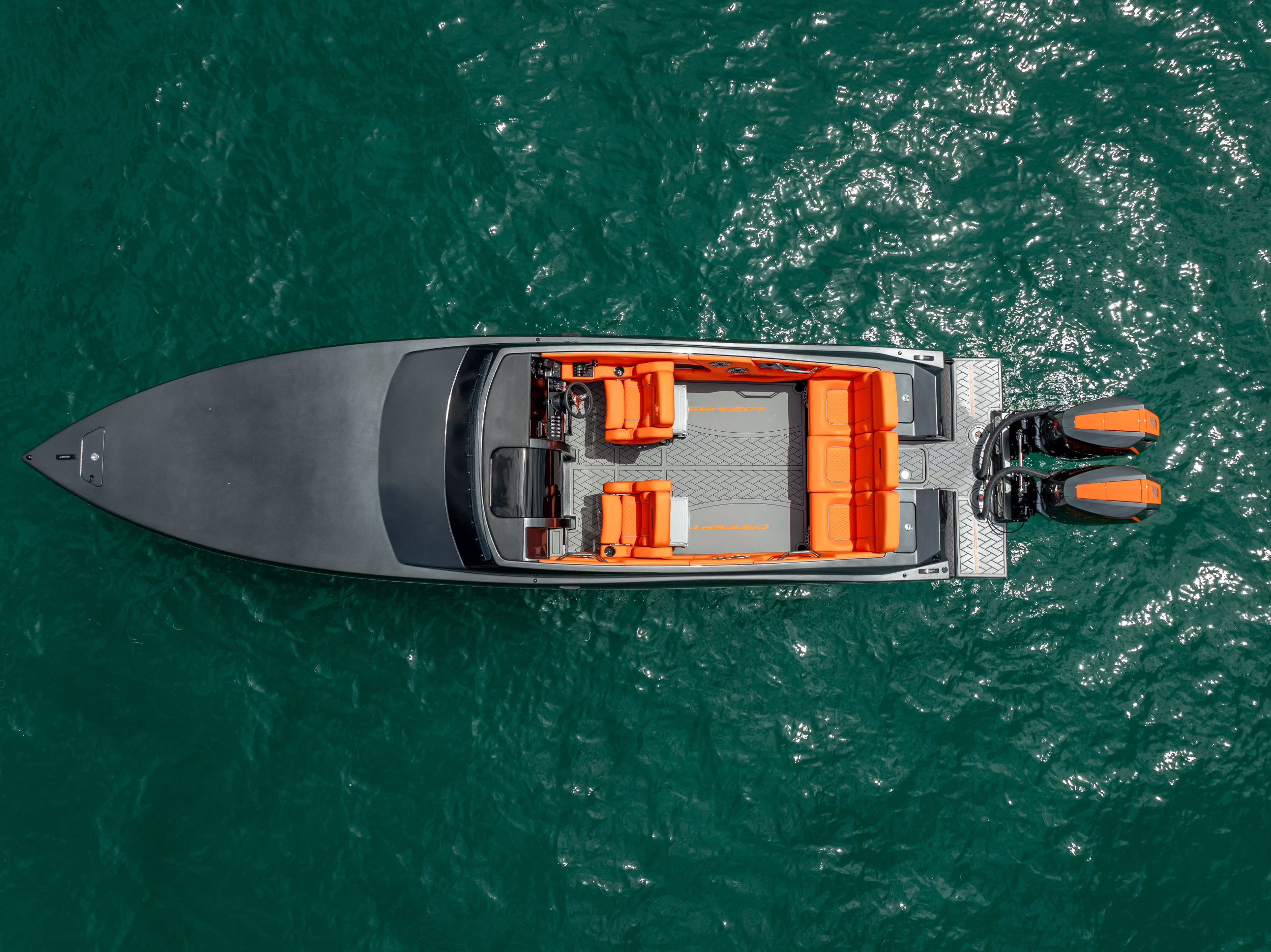 Aerial view of a modern sport boat with orange seating and two outboard motors on the water.