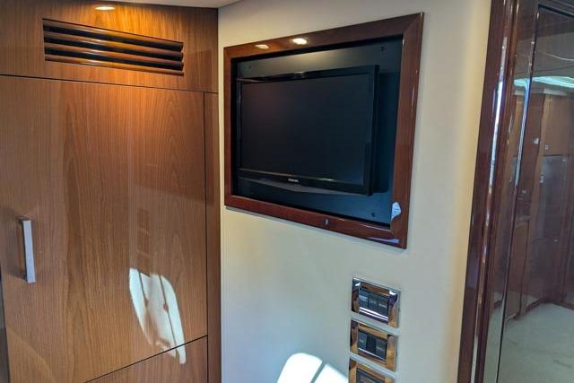 Interior of 2013 Sea Ray 470 Sundancer with wall-mounted TV and wooden cabinetry.