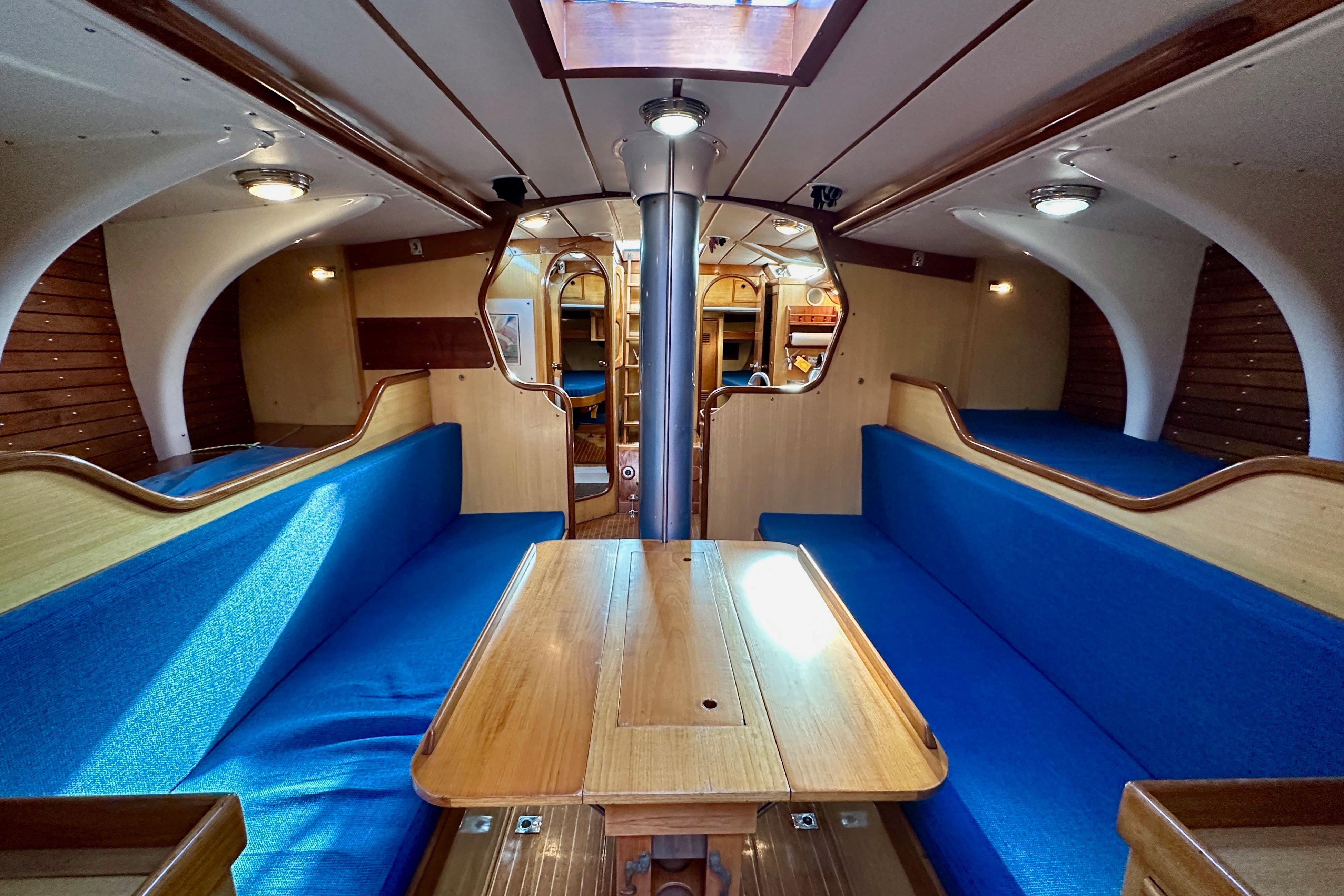 1973 Nautor Swan 44 yacht interior with blue seating and wooden table.