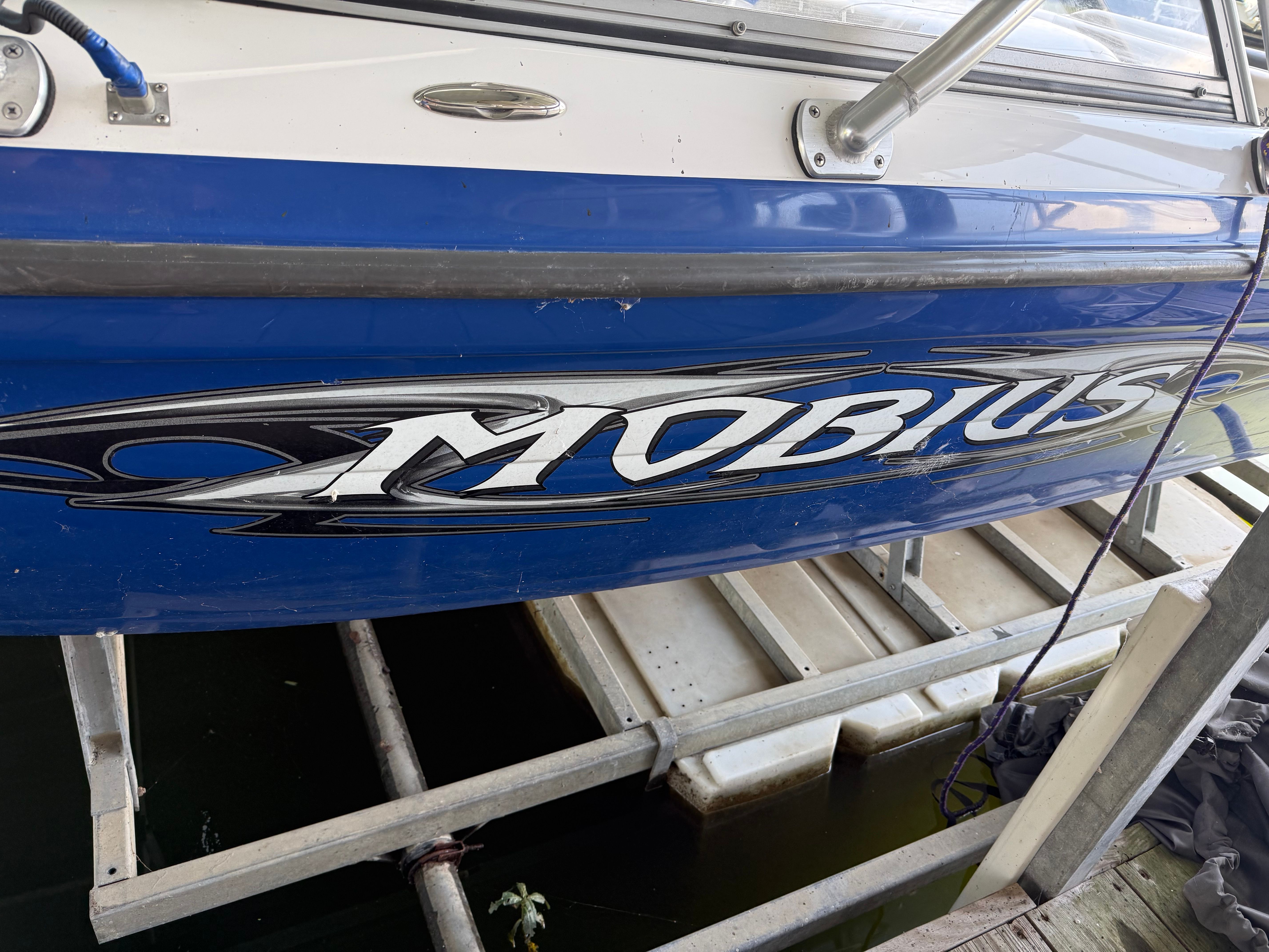 Close-up of a blue 2005 Moomba Mobius LS boat docked at a pier.