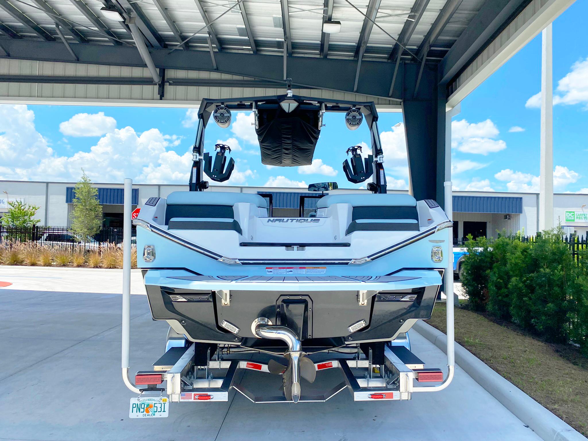 2024 Nautique Super Air Nautique G21 boat under a metal canopy, rear view.
