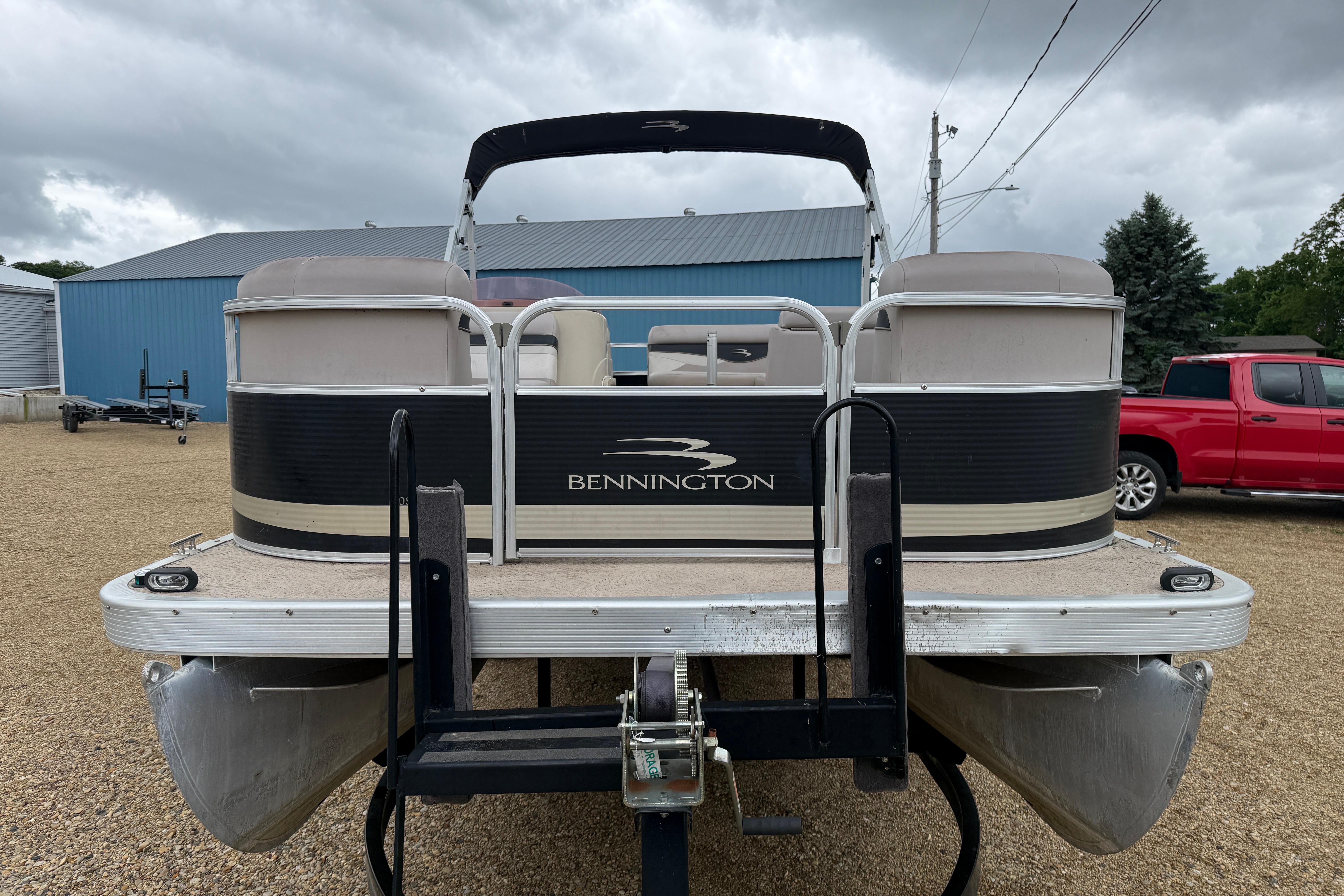 2010 Bennington 20SLi pontoon boat on trailer, parked outdoors under cloudy sky.