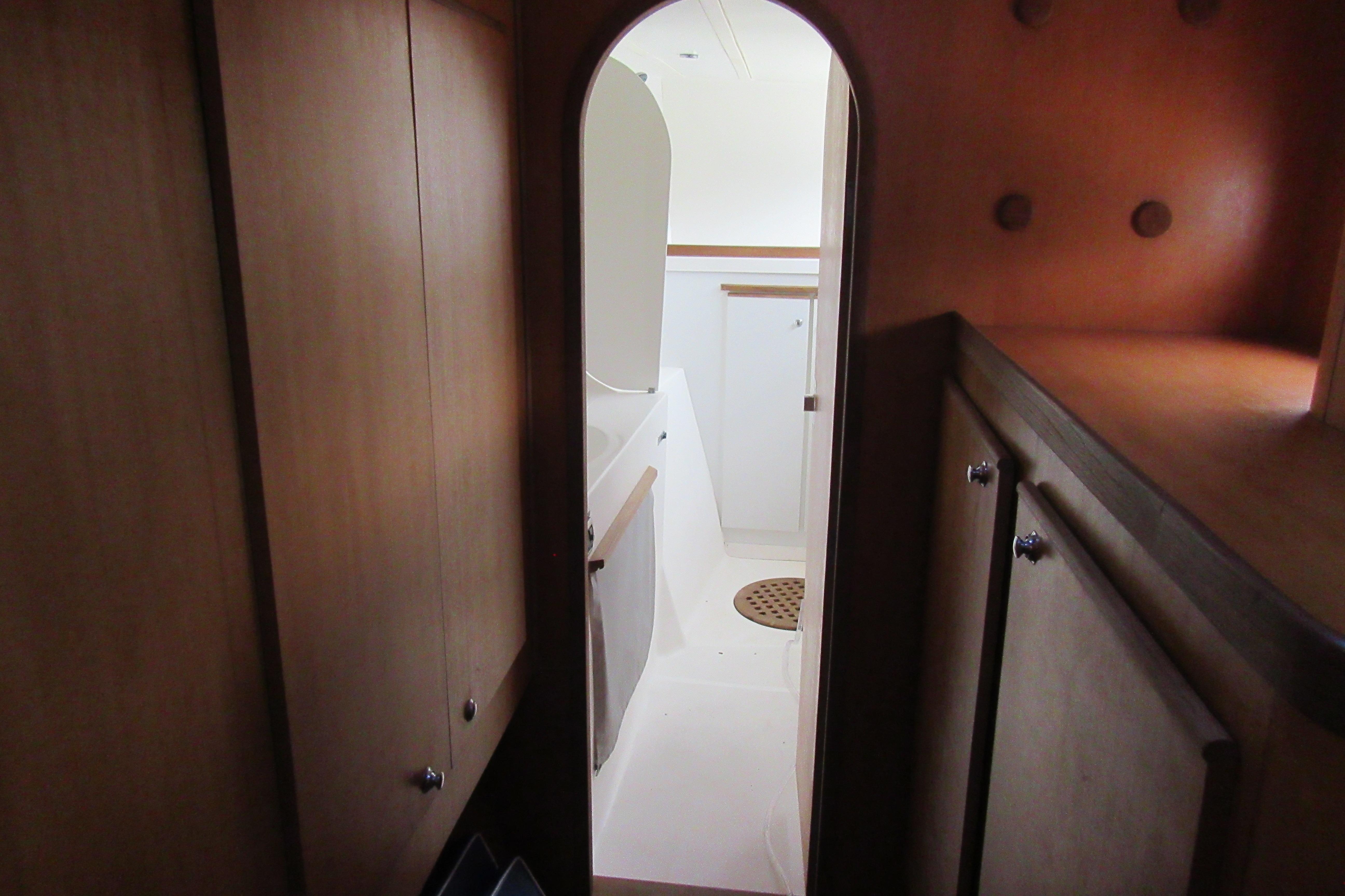 Interior view of 2001 Catana 471 yacht, featuring wooden cabinetry and a compact bathroom.
