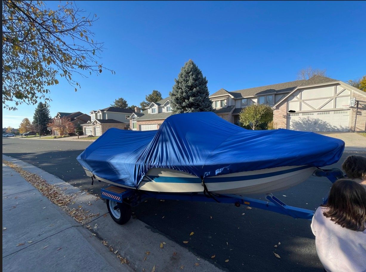 Covered boat on trailer in residential street, Larsen 13 model from 1962.