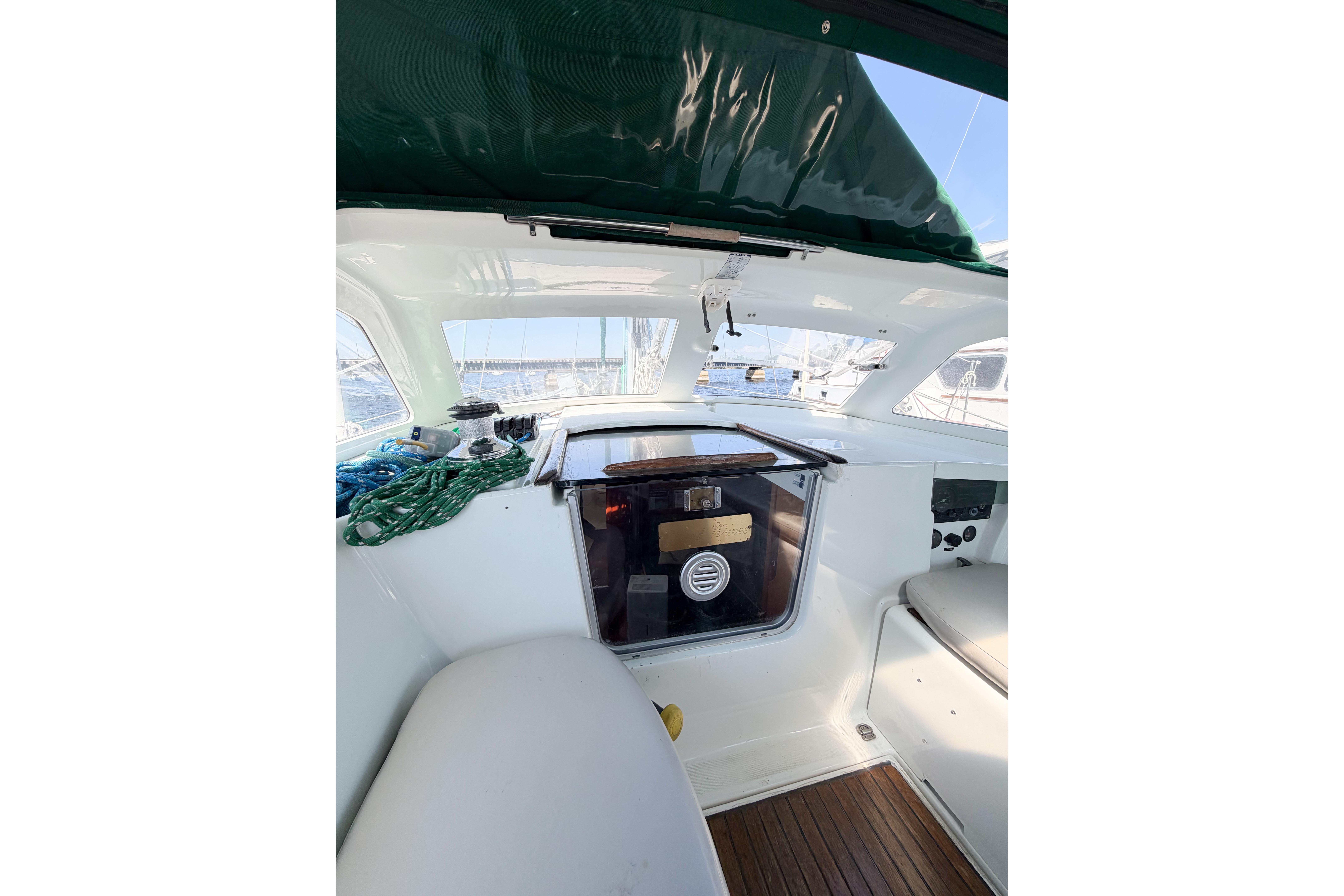 Cockpit of 2002 Beneteau Oceanis 42CC sailboat with green canopy and wooden flooring.