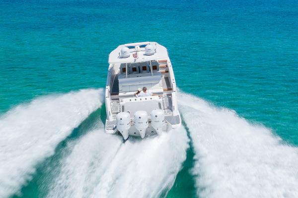 Manufacturer Provided Image: 2026 Regal 38 SAV boat cruising on clear turquoise water, rear view.