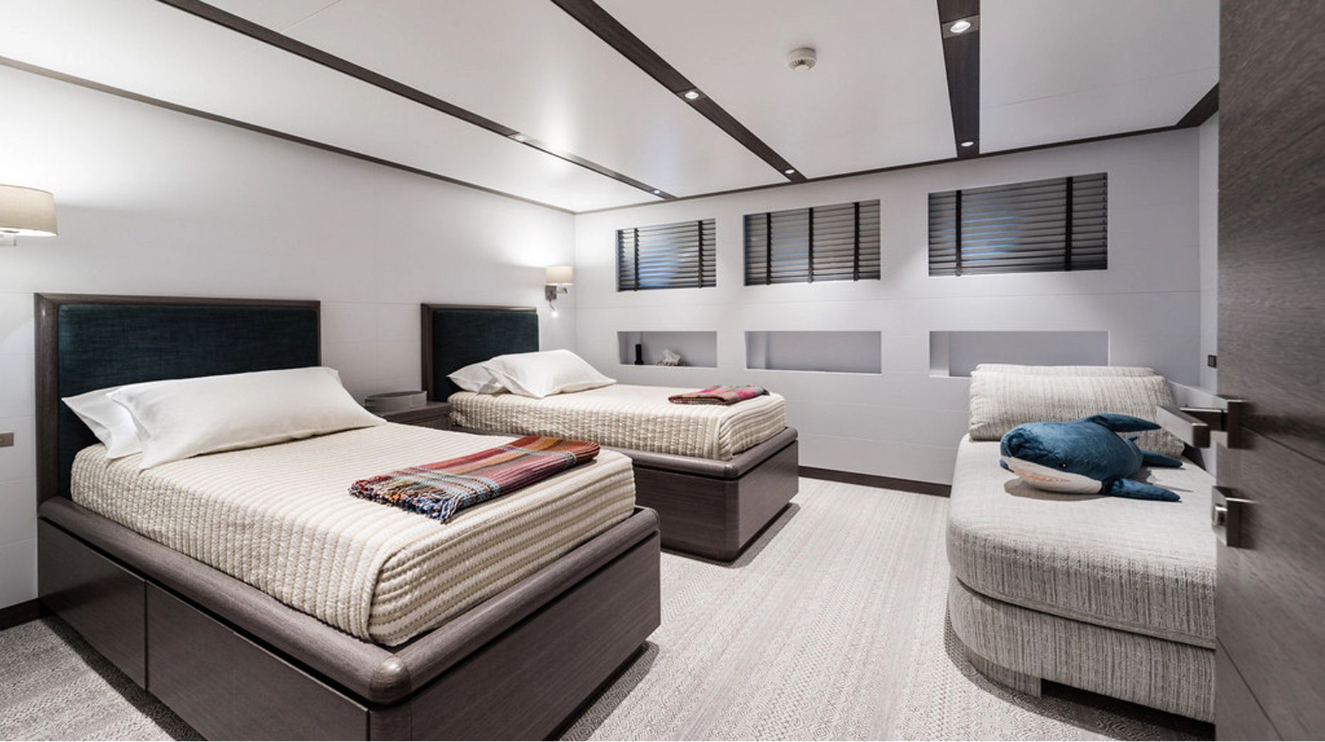 Two single beds in a modern cabin with sleek decor and a sofa.
