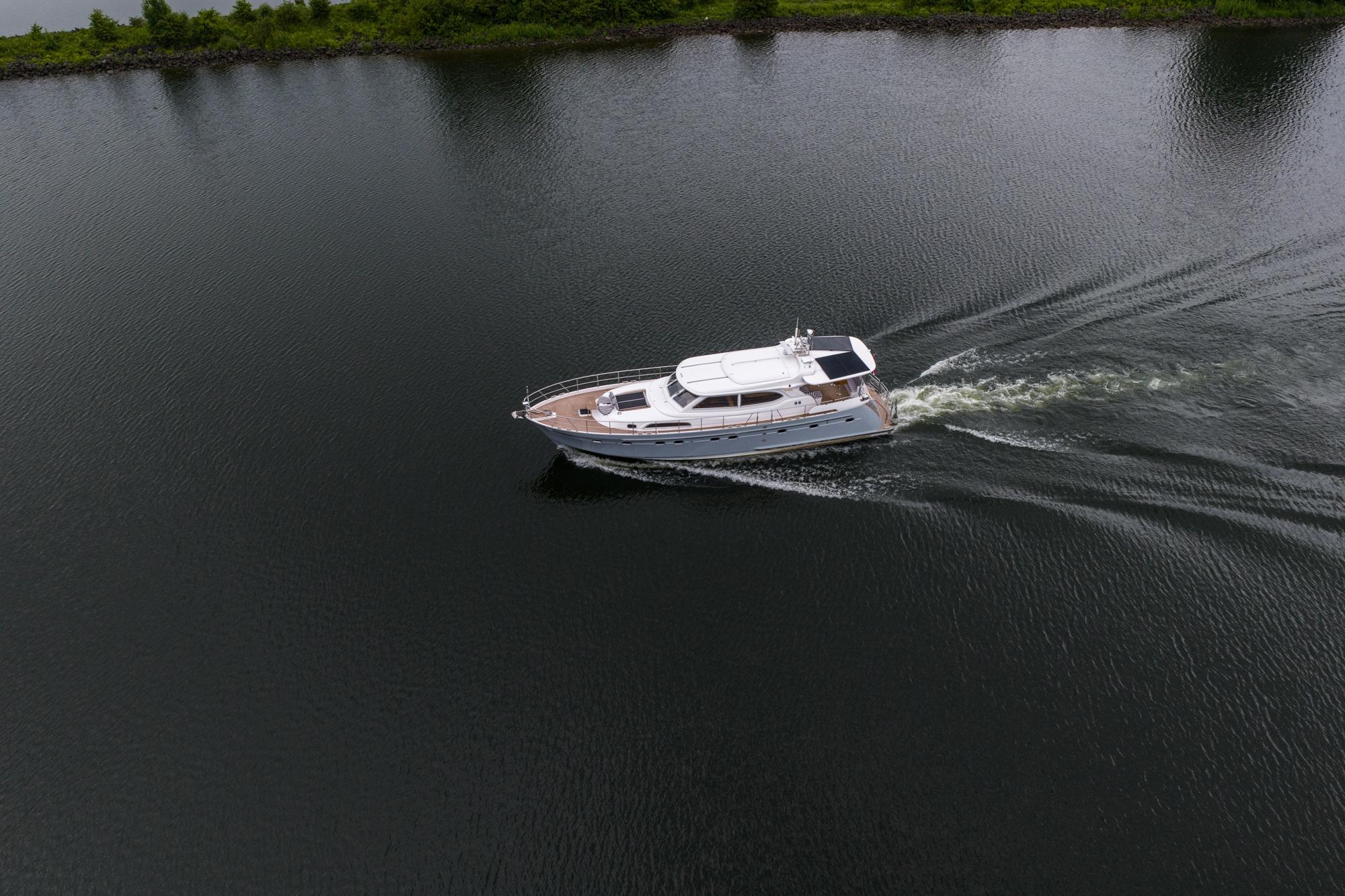 Aerial view of 2025 Elling E6 yacht cruising on calm water near lush shoreline.