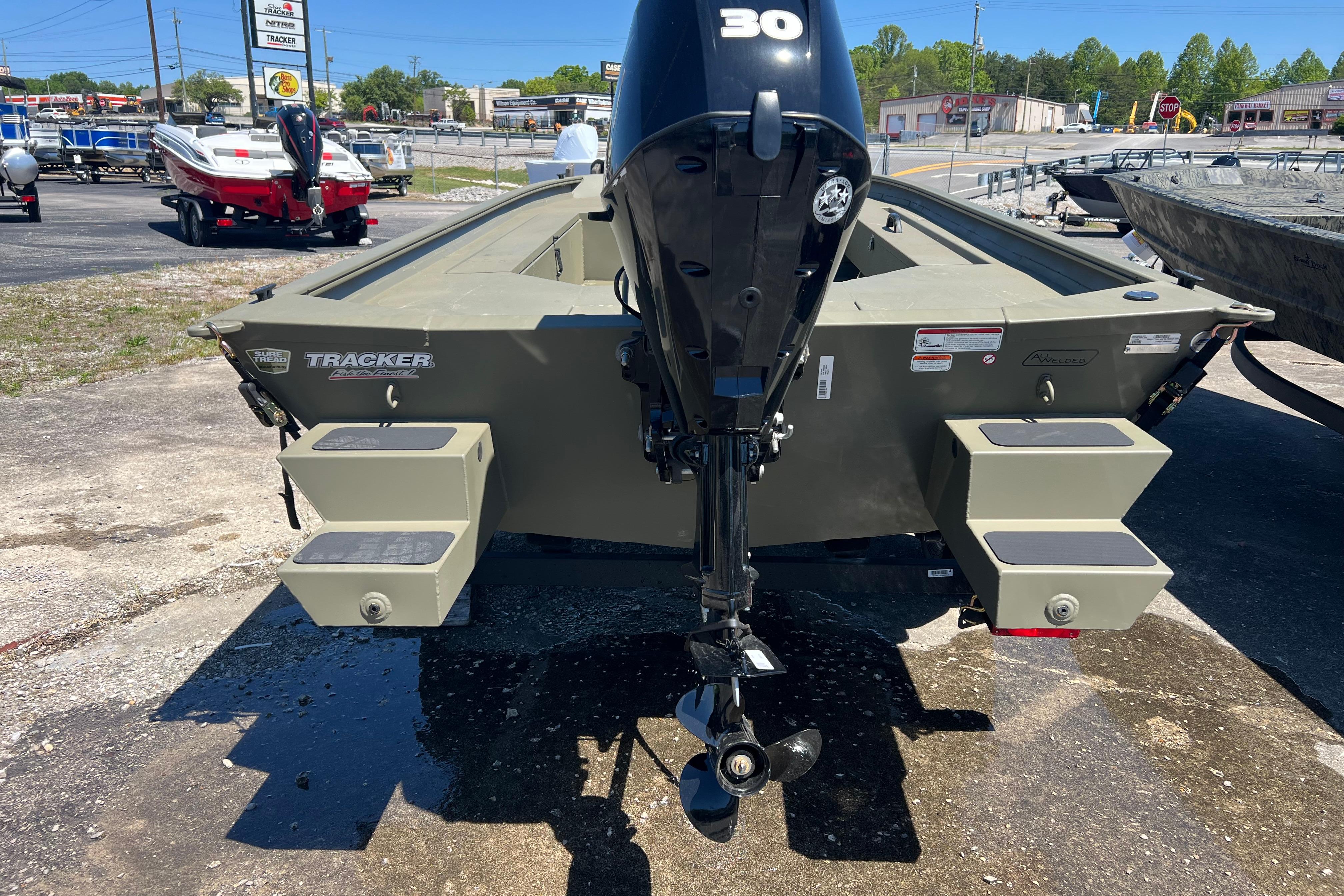 2026 Tracker Grizzly 1654 T Sportsman boat with outboard motor, parked outdoors.