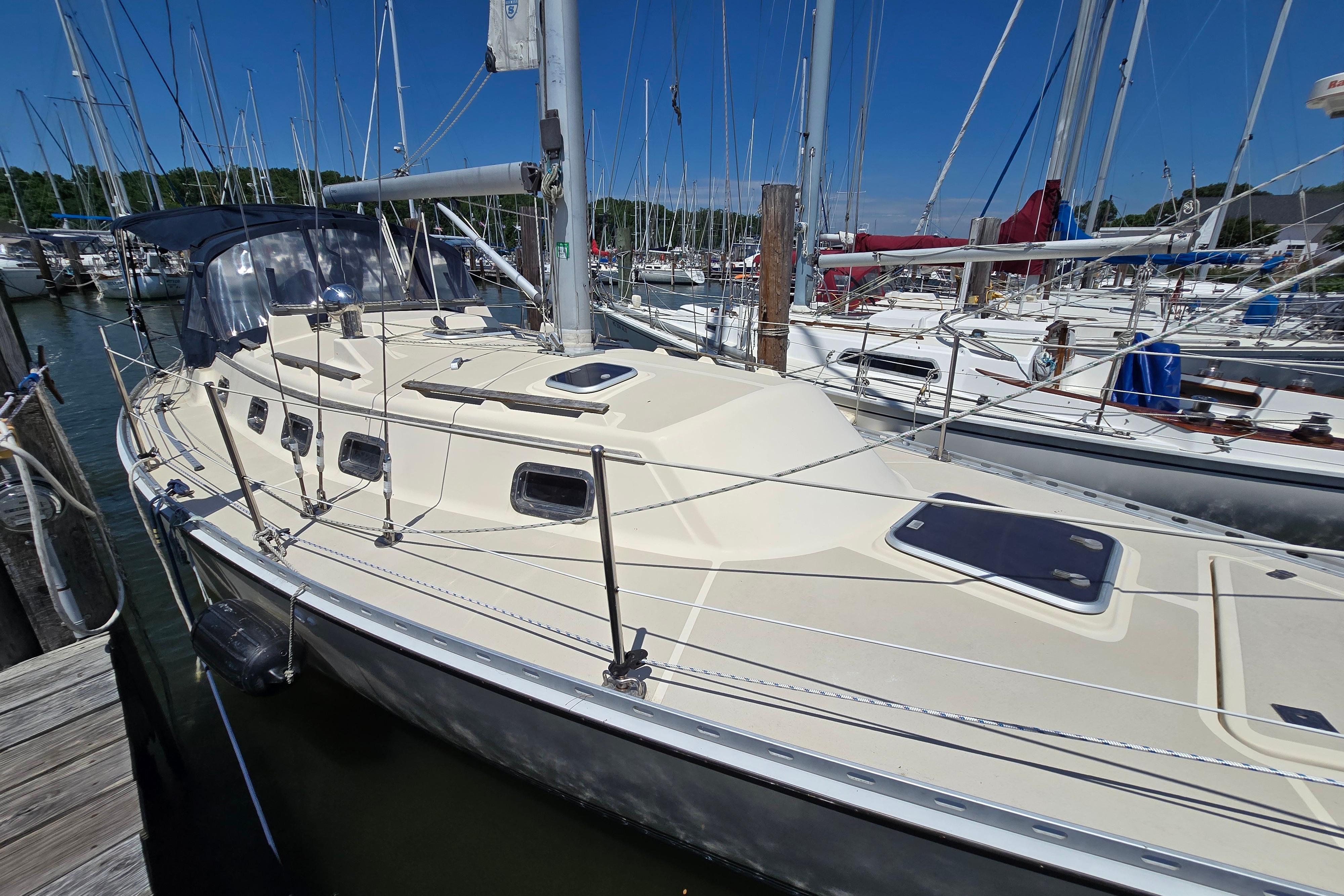 Sailboat docked in marina, 1993 Caliber 35 model, sunny day, surrounded by other boats.