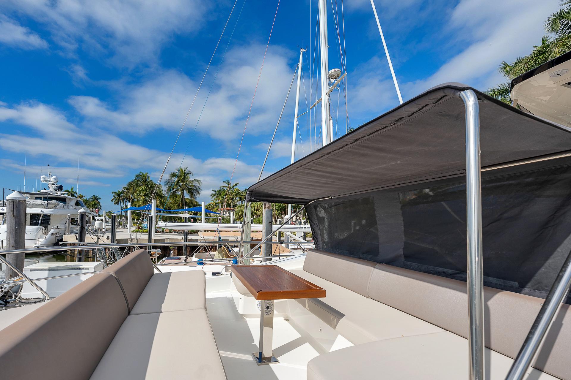 Astondoa 66 yacht 2022, featuring spacious deck seating under a canopy, docked at marina.