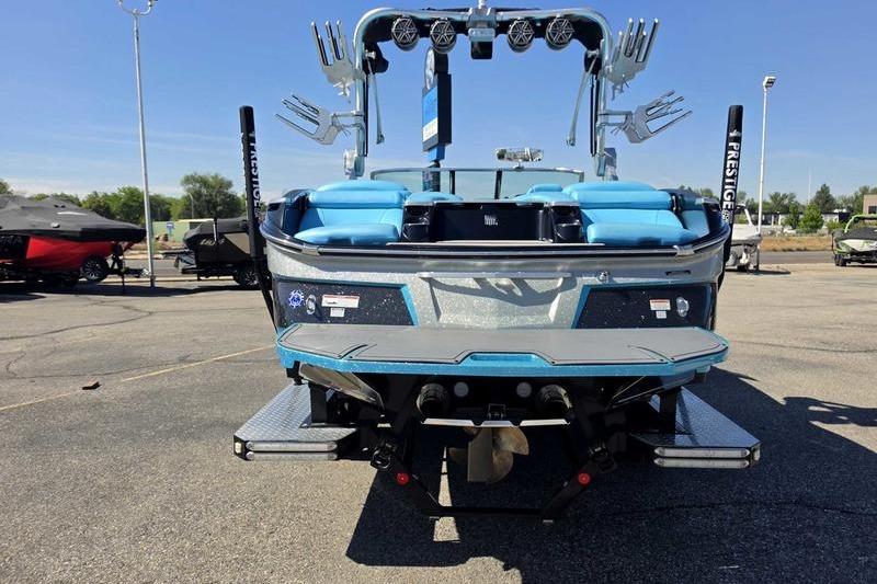2017 MasterCraft X23 boat with blue seating and wakeboard tower, parked outdoors.