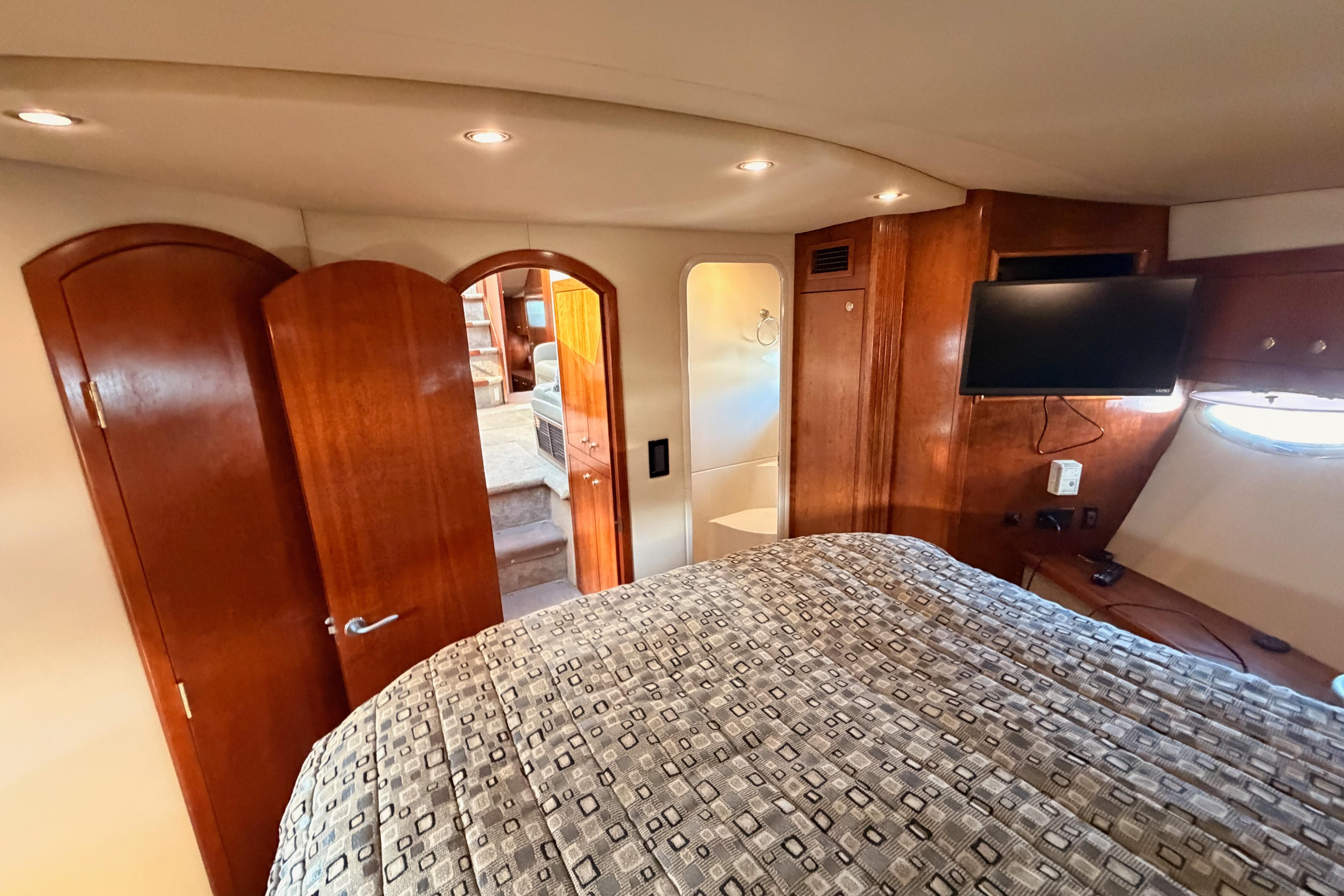Luxurious 2005 Cruisers Yachts 405 Express Motoryacht bedroom with wood accents and TV.