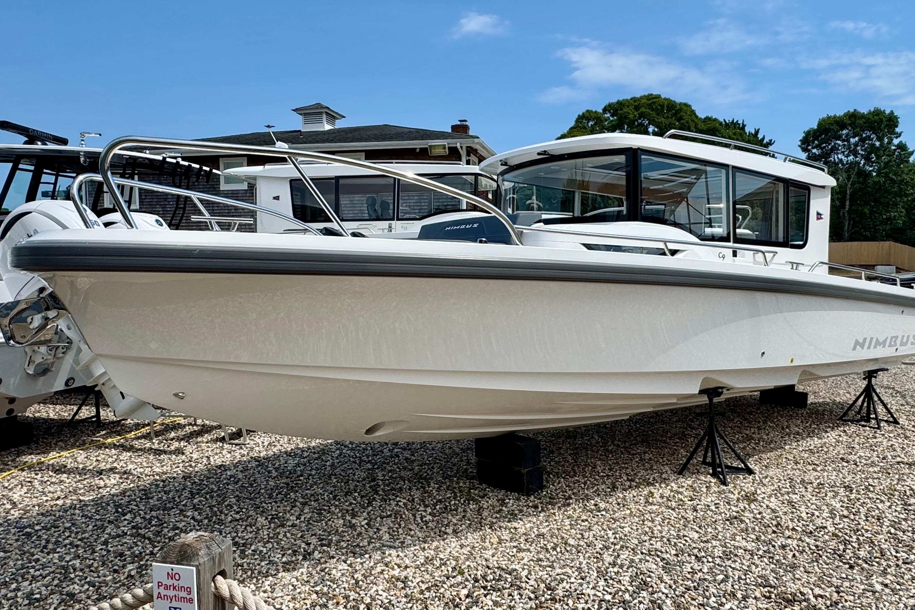 A 2026 Nimbus Commuter 9 boat is on a gravel lot. It features a modern design.