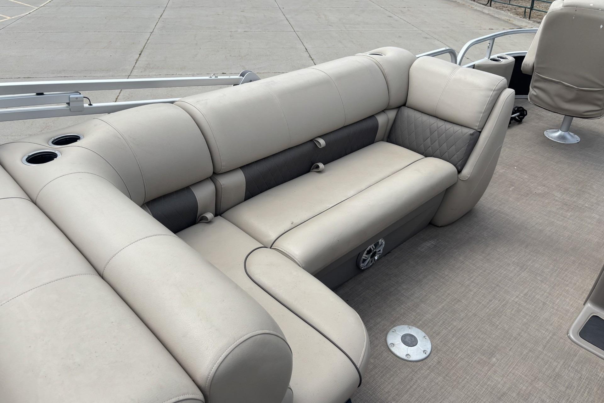 2023 Sun Tracker SportFish 20 DLX pontoon boat interior with beige seating and cup holders.