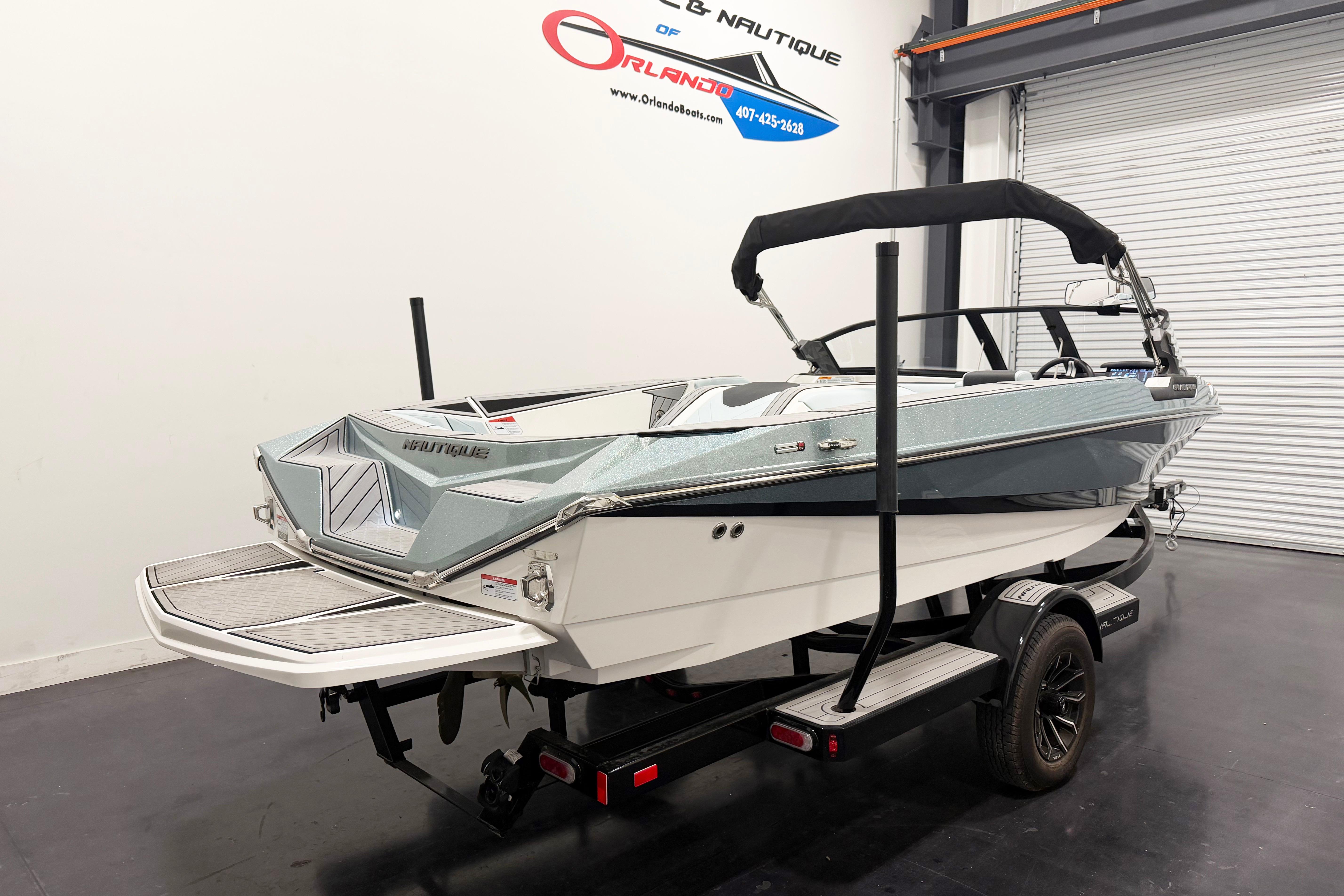 2025 Nautique Ski Nautique boat on trailer in showroom, rear view.