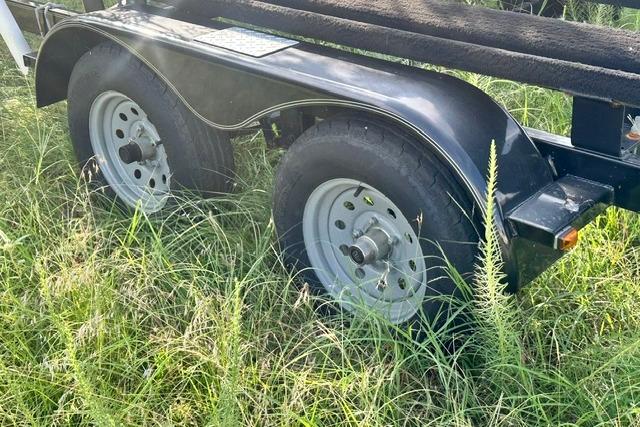 Trailer wheels of a 2019 Sun Tracker Party Barge 22 XP3 in grassy area.