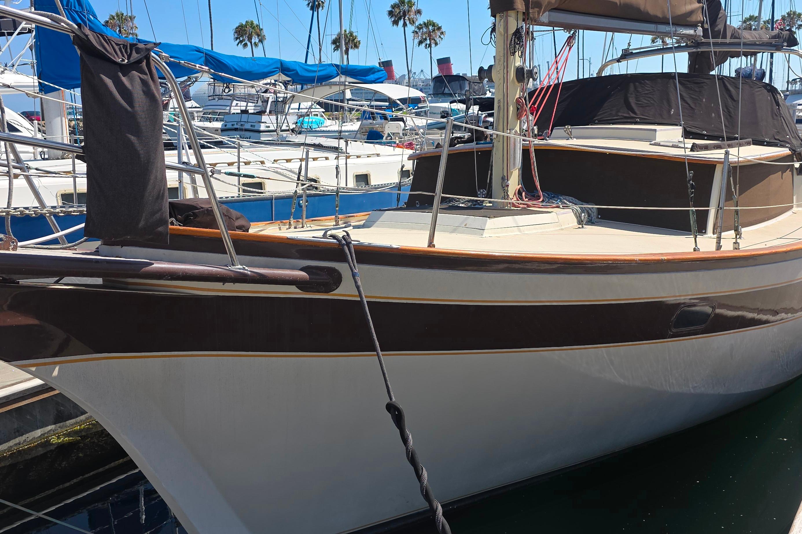 1978 Islander Freeport 41 sailboat docked at marina with blue tarps and palm trees.