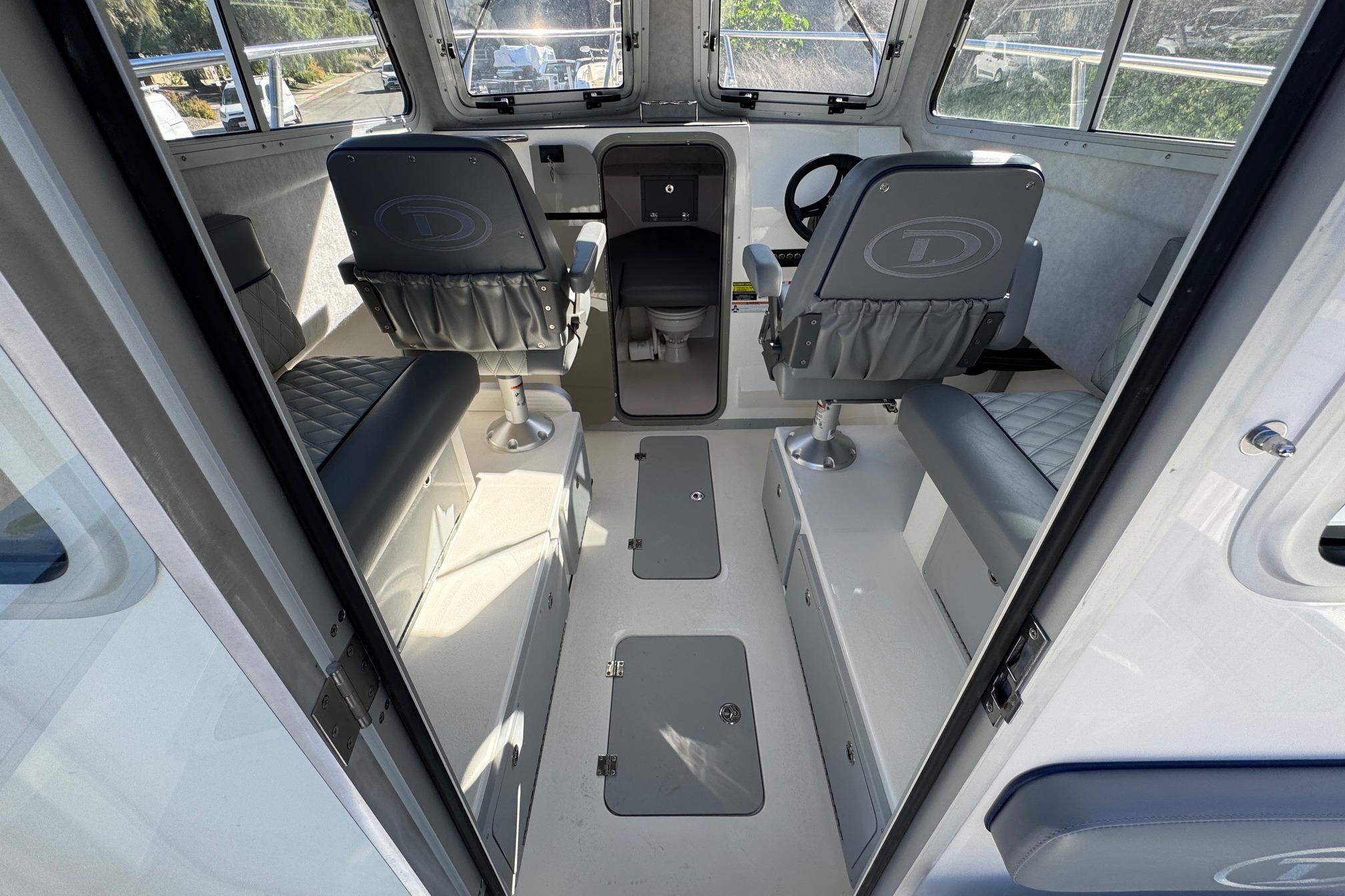 Interior of 2026 Defiance Admiral 250 EX boat, featuring seating and steering area.