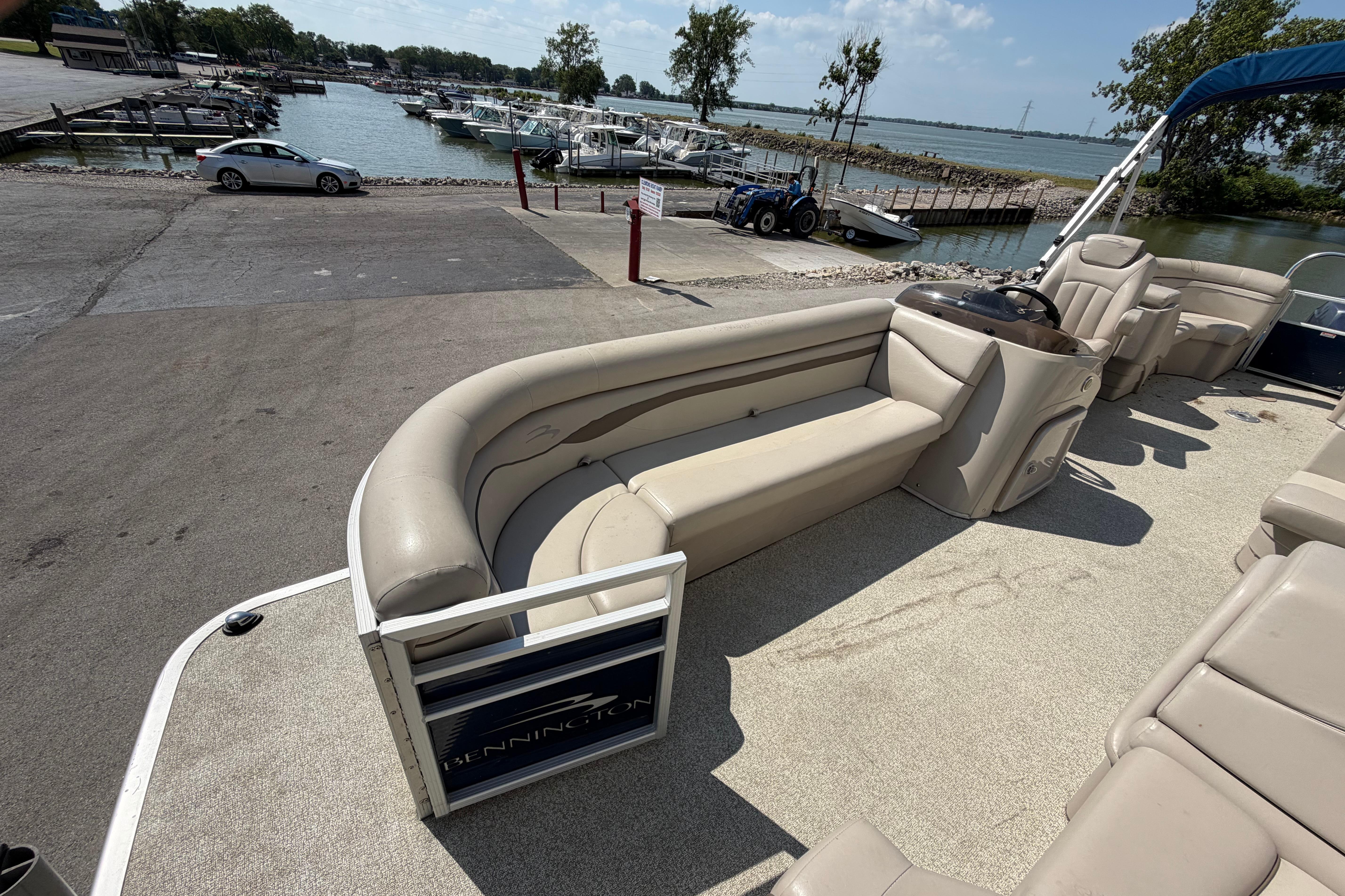 2017 Bennington 25 SSXAPG pontoon boat interior with beige seating, docked near a marina.