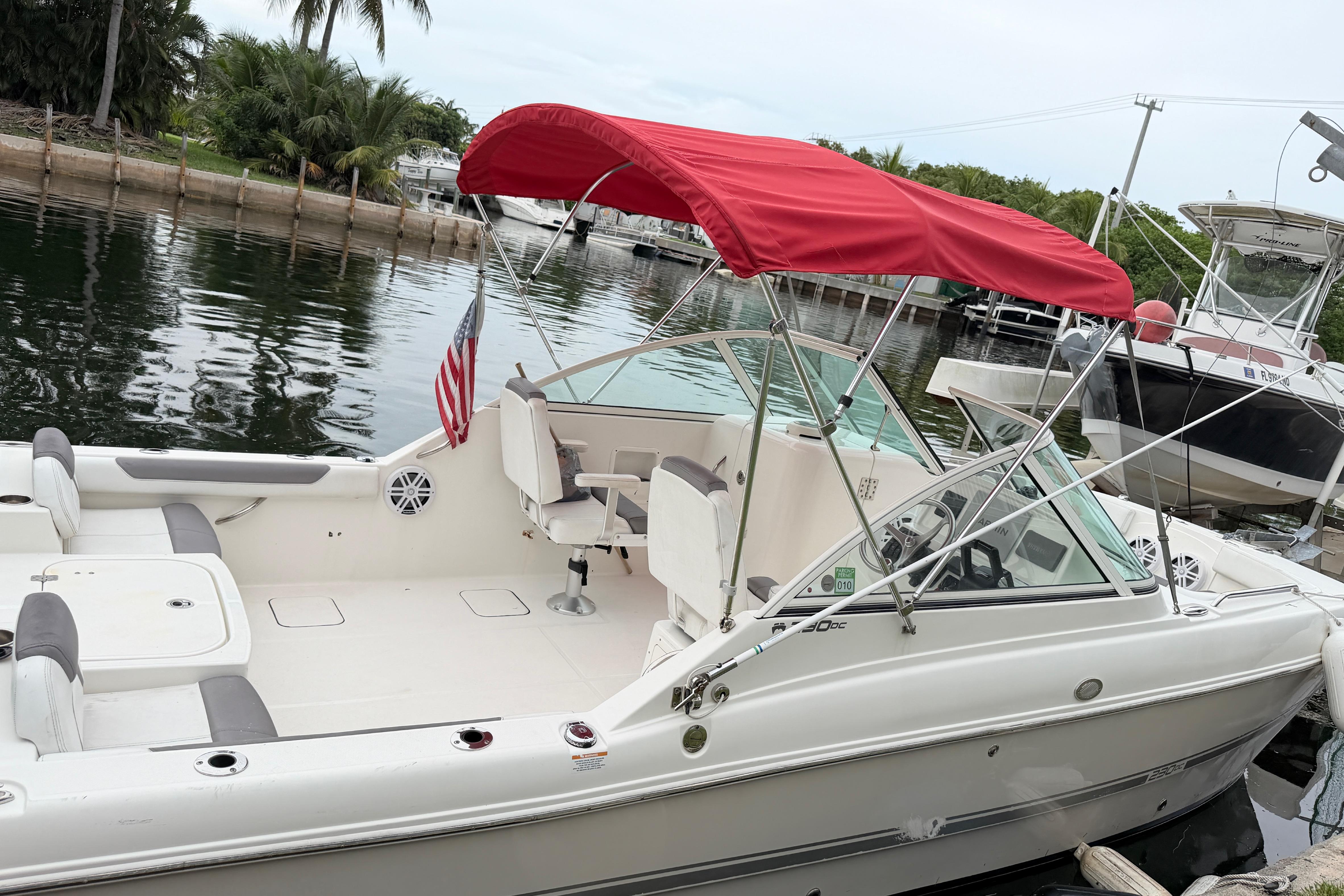 2019 World Cat 230 DC boat with red canopy docked by the water.