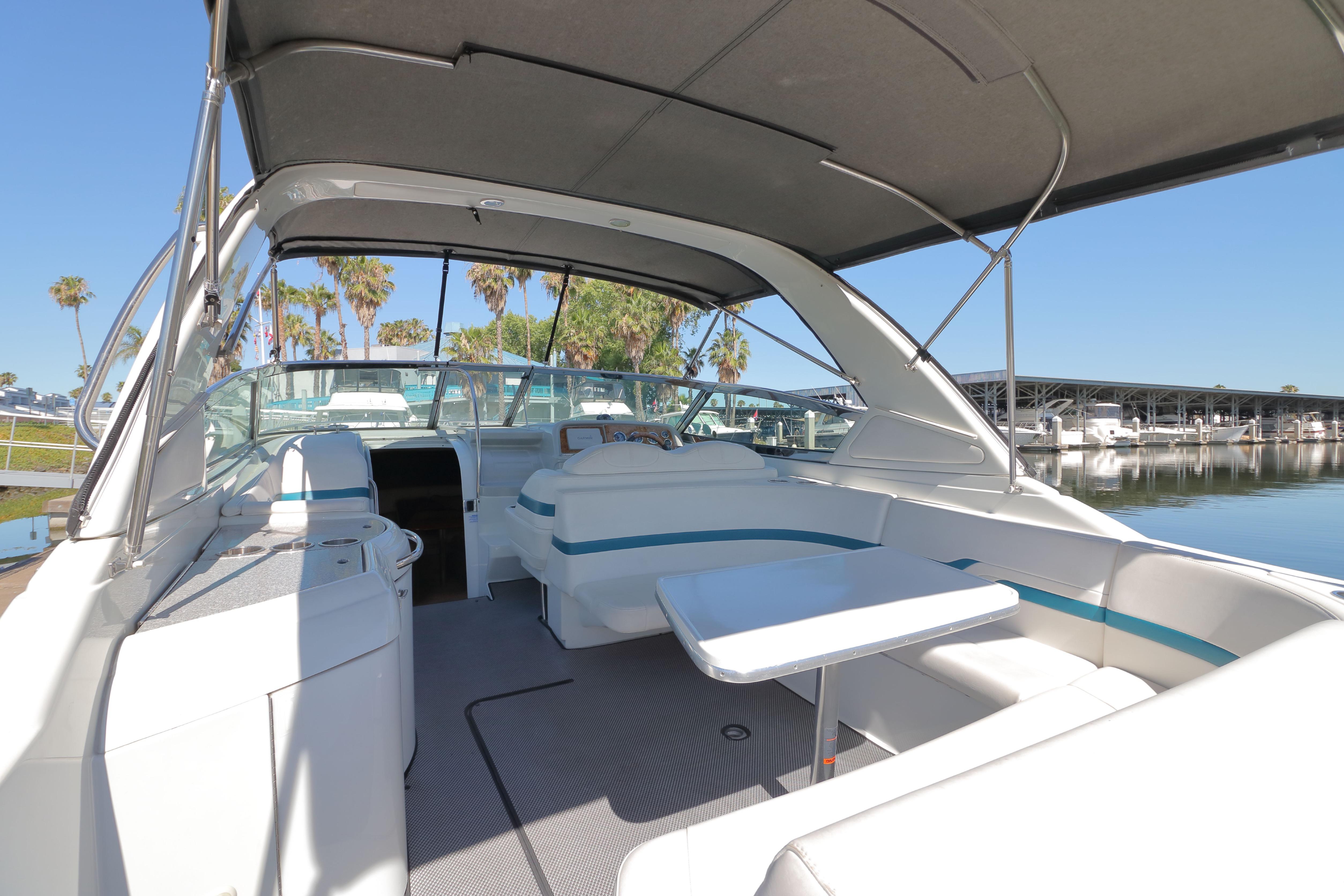 2006 Formula 330 Sun Sport boat interior with seating and table, docked near palm trees.