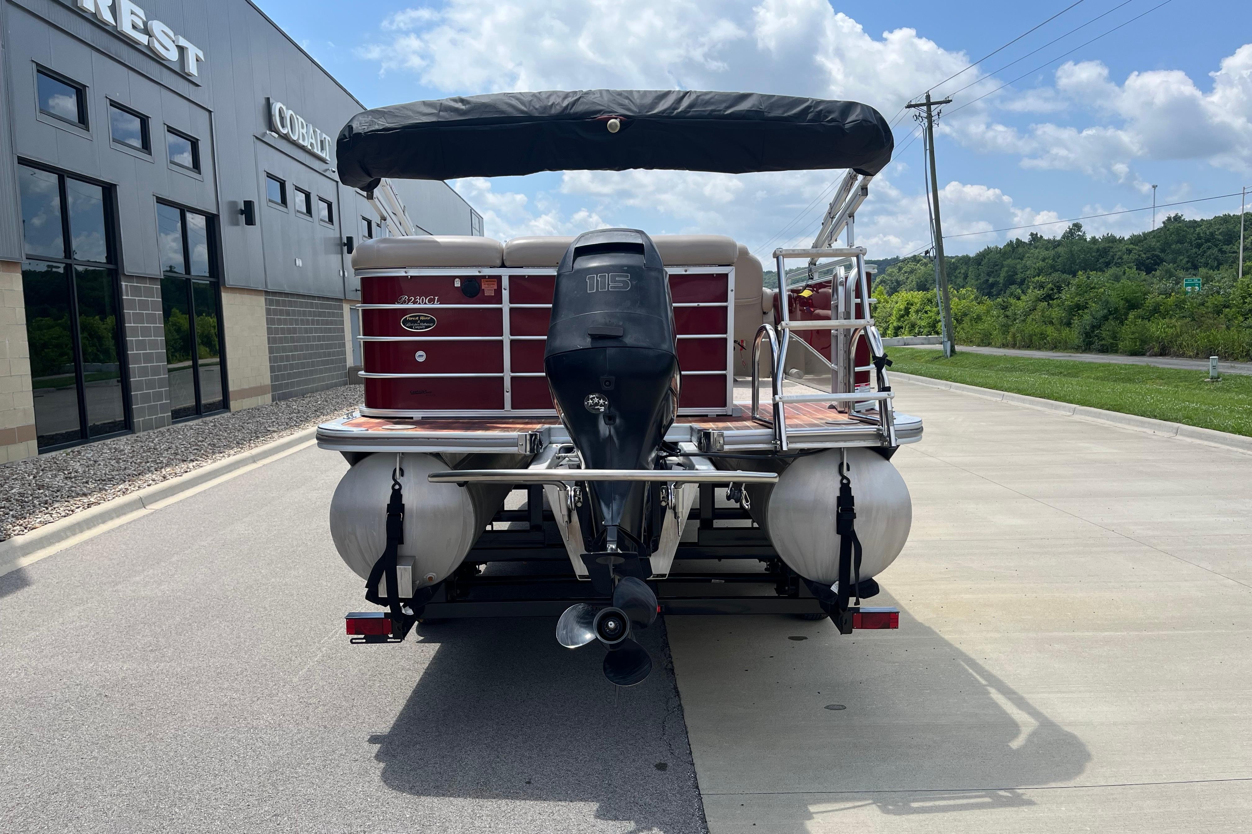 2013 Berkshire 230CL CTS pontoon boat with outboard motor, parked near dealership.