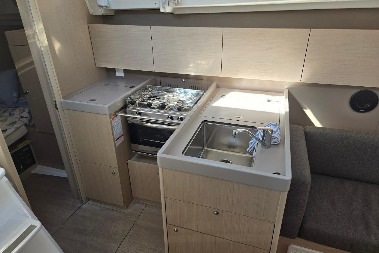 2023 Beneteau Oceanis 38.1 yacht interior kitchen with stove, sink, and cabinets.