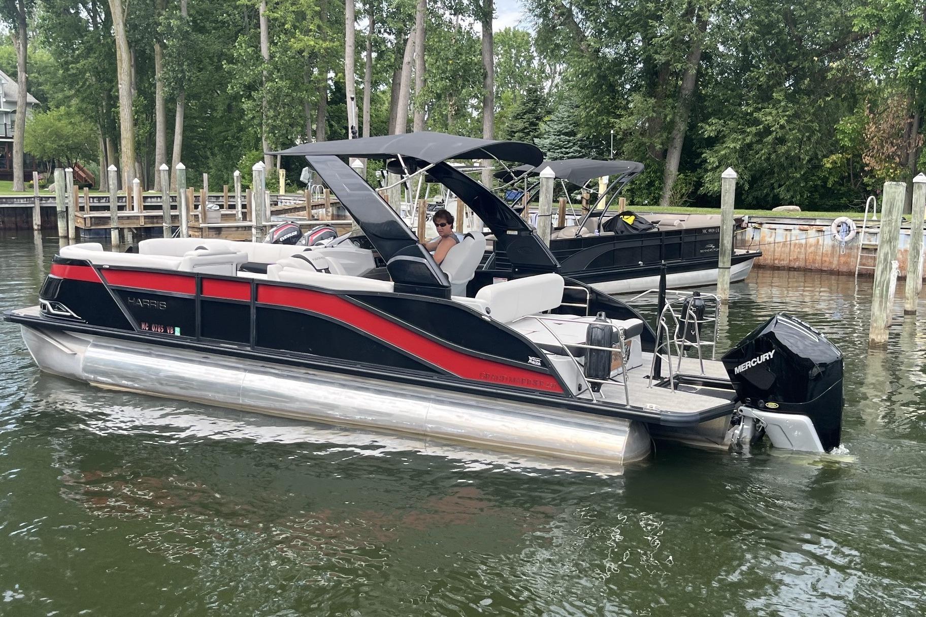 2024 Harris Grand Mariner 250 pontoon boat docked on a calm lake.