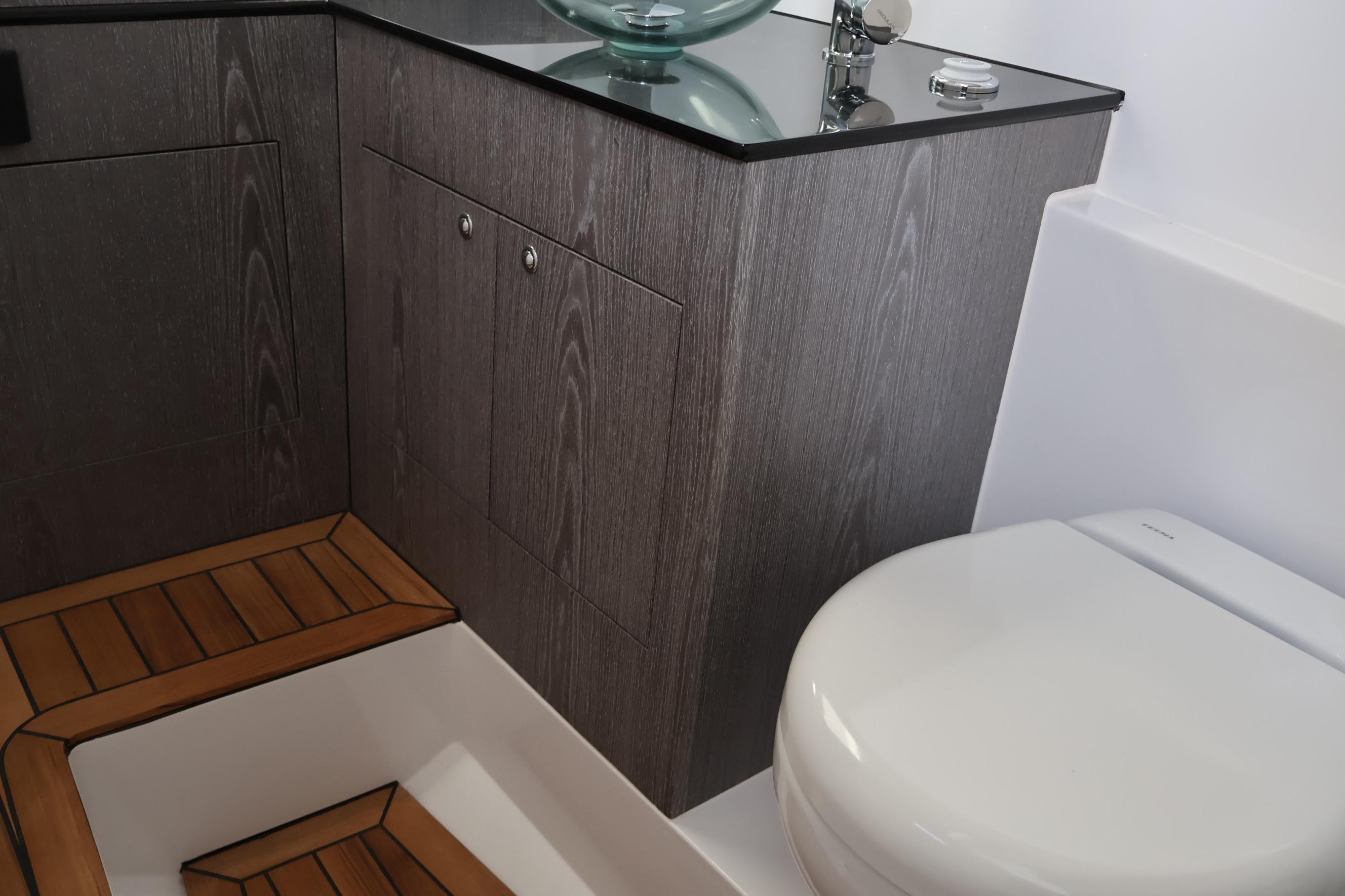 Modern bathroom interior on Pirelli 30 yacht, featuring sleek wood cabinetry and glass sink, 2026 model.