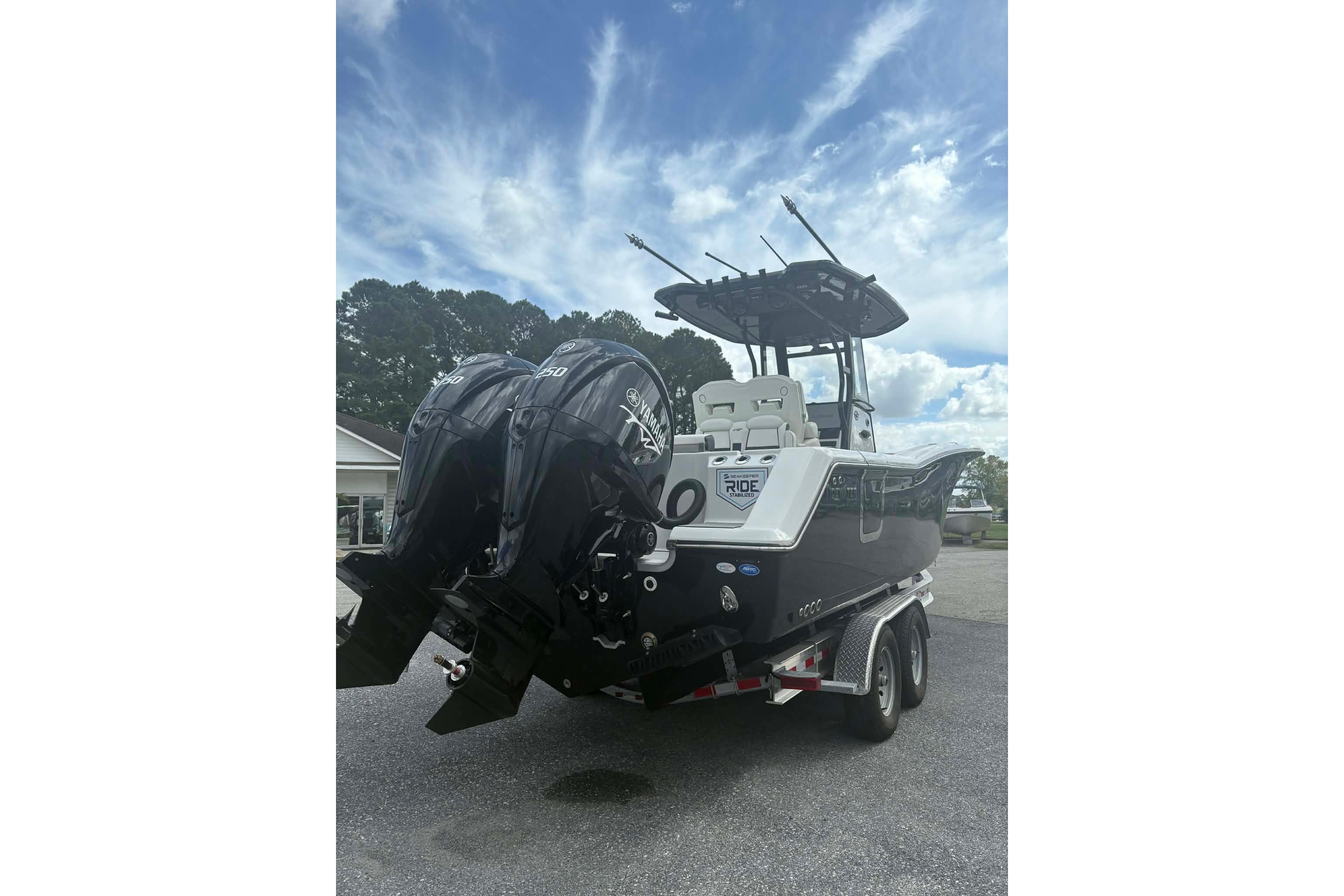 2026 Tidewater 282 CC Adventure boat with dual engines on a trailer under a cloudy sky.