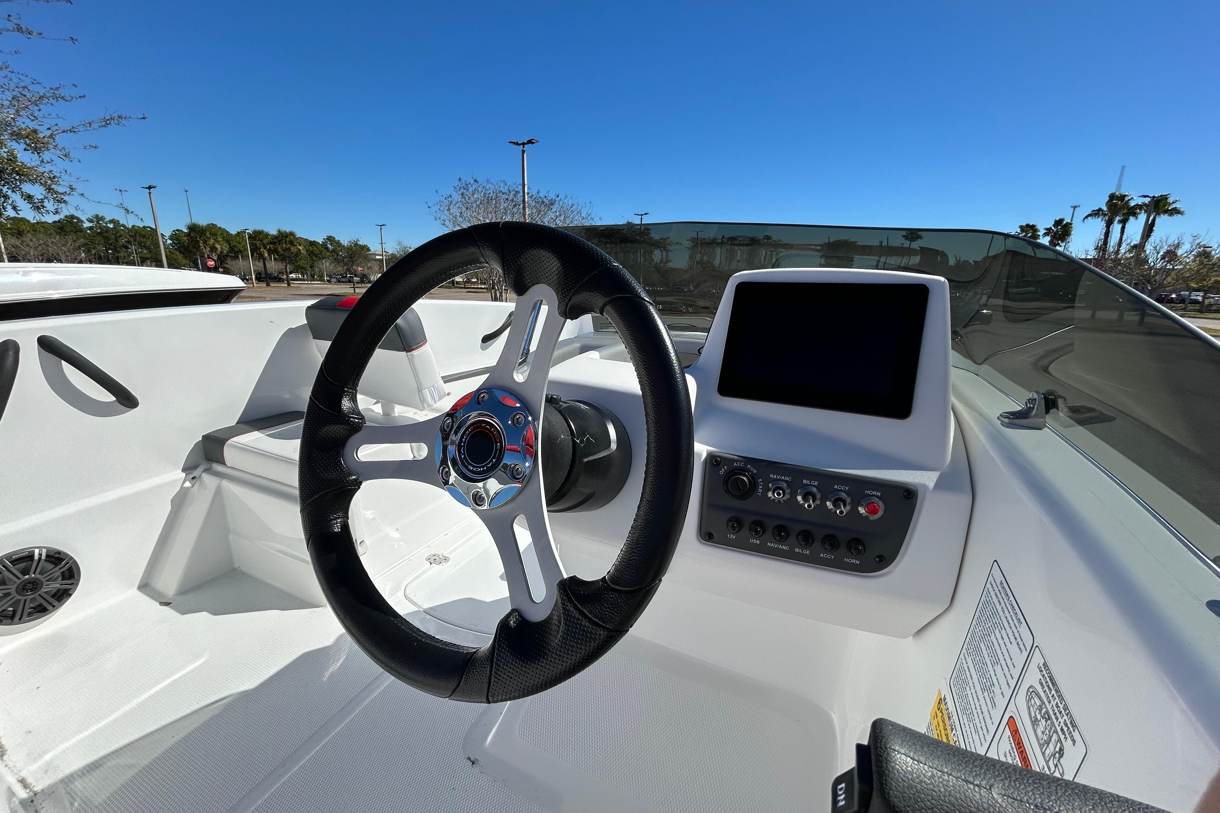 2026 Tahoe T16 boat interior with steering wheel and control panel under clear blue sky.