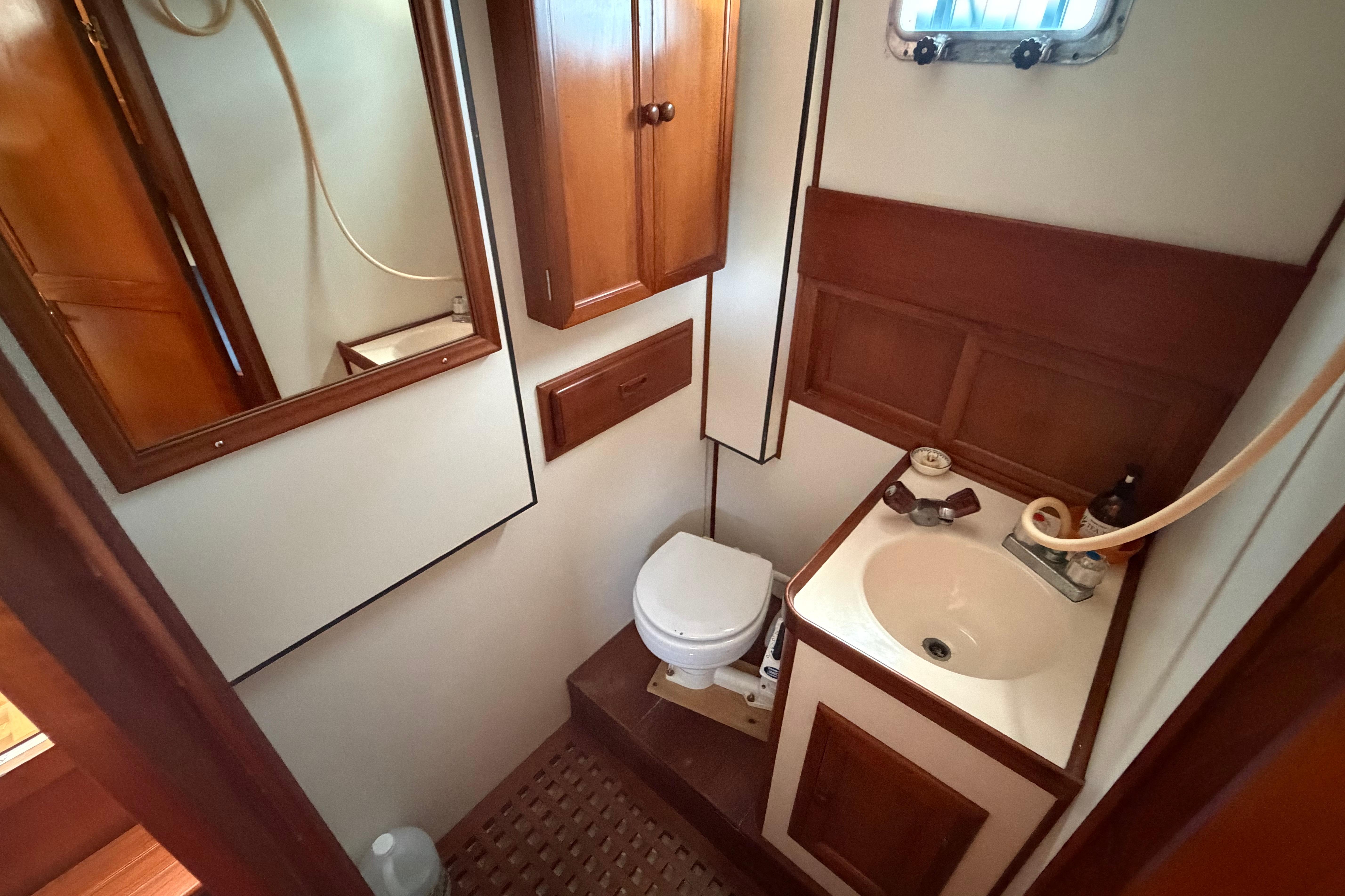 1987 Marine Trader 36 yacht bathroom with wooden cabinetry, sink, and toilet.
