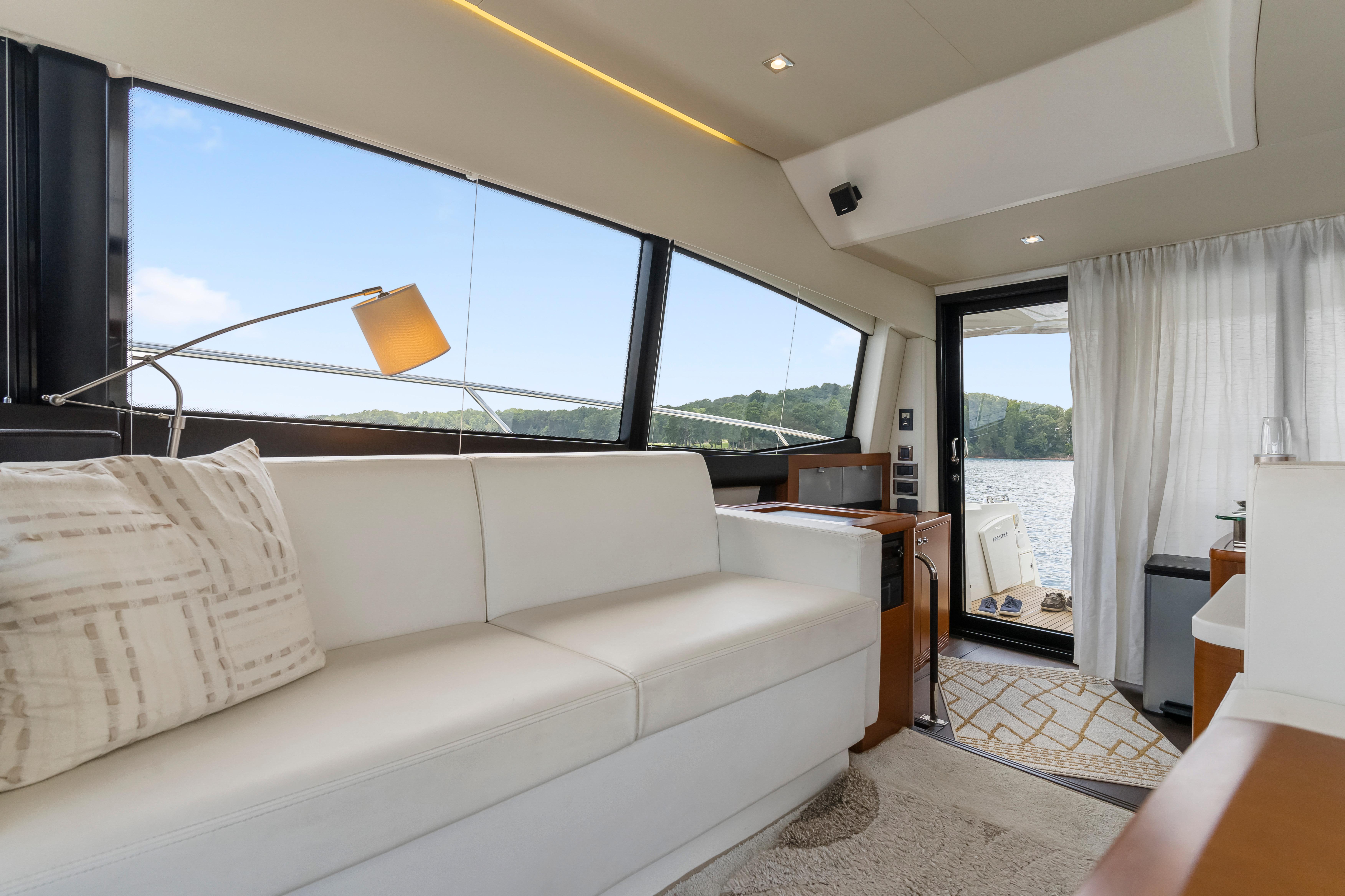 Luxurious interior of a 2017 Prestige 500 yacht with white seating and scenic window views.