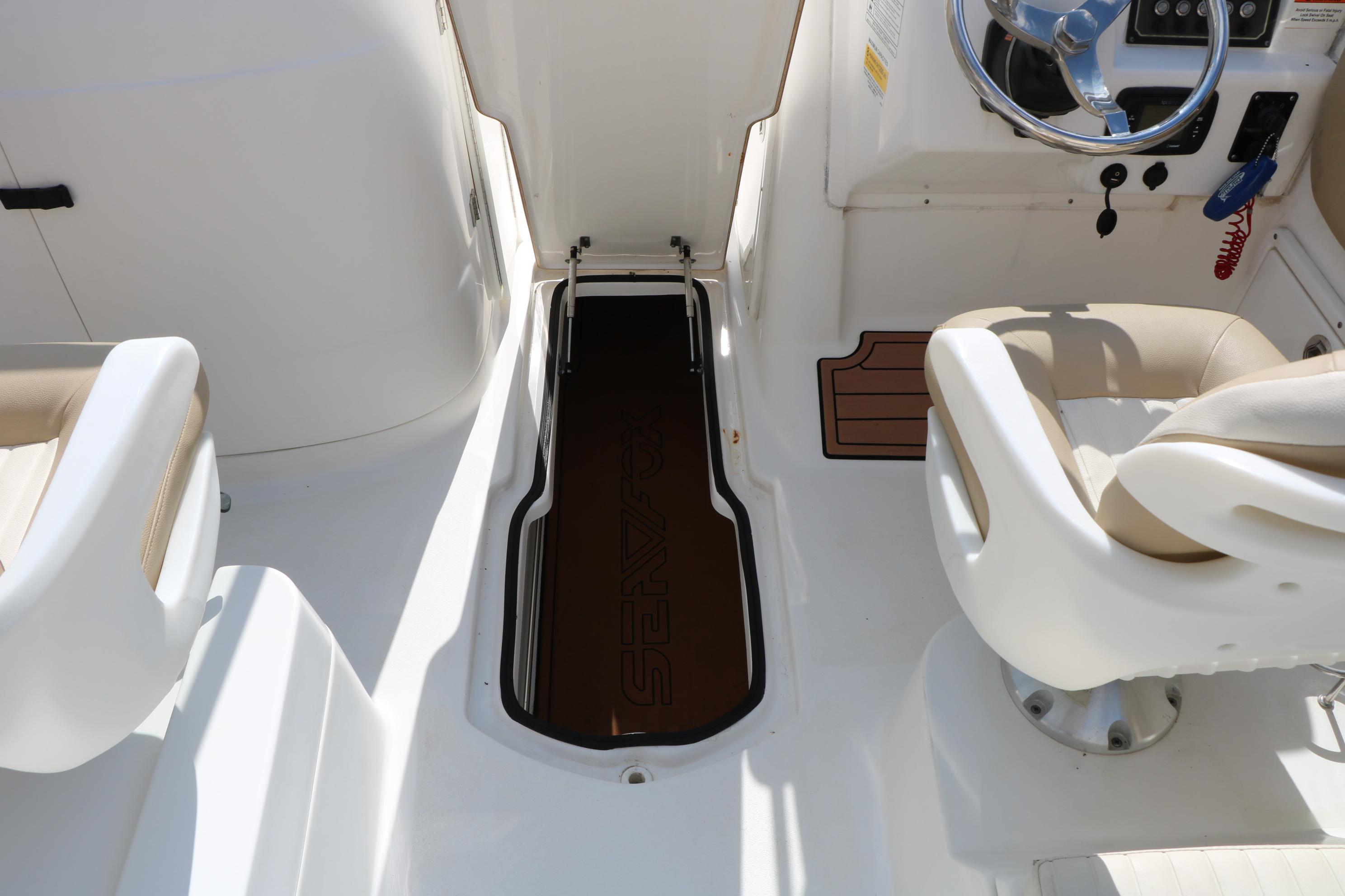 2017 Sea Fox 226 Traveler boat interior with open storage compartment and steering wheel.