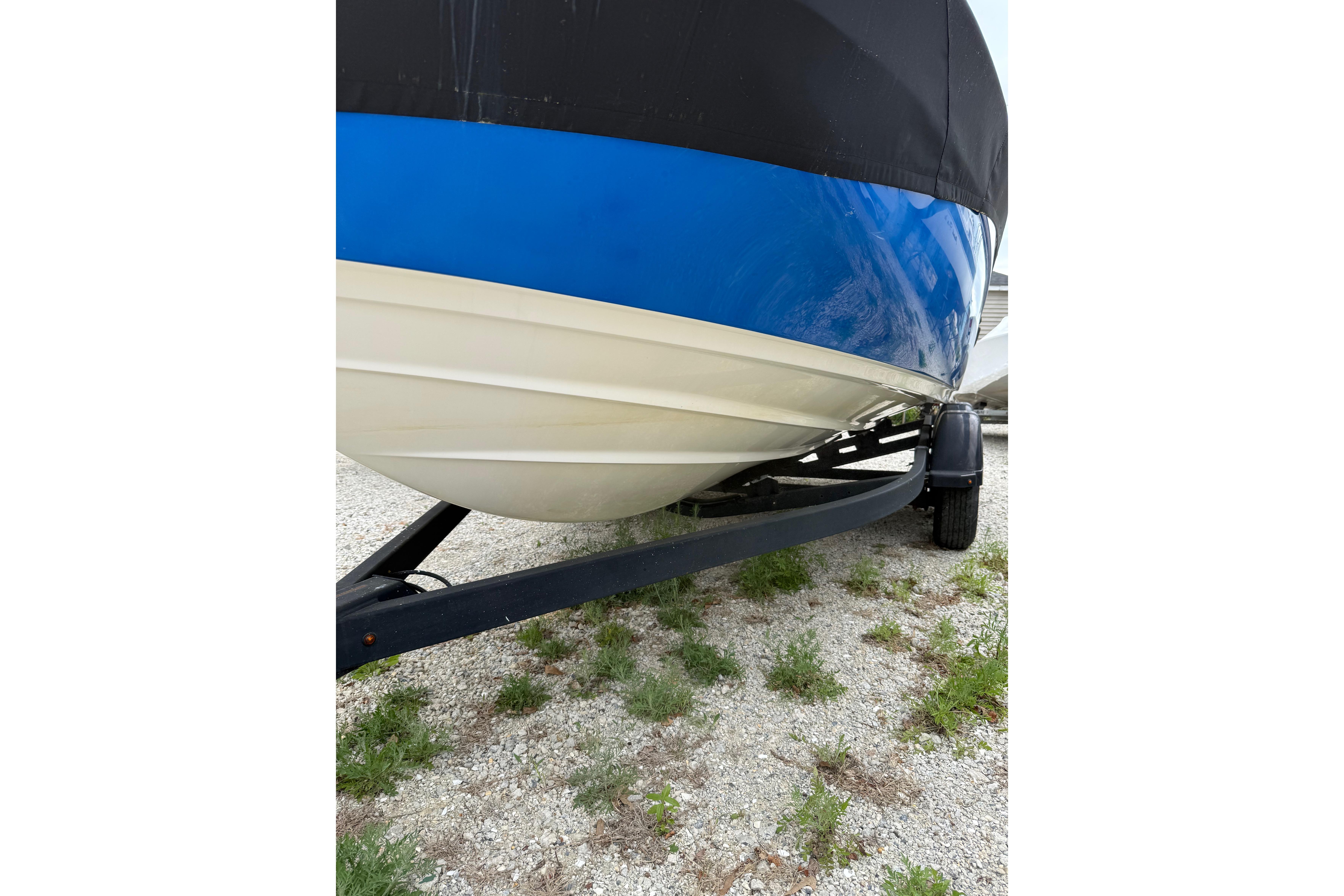2019 Yamaha Boats AR210 on trailer, blue and white hull, parked on gravel.