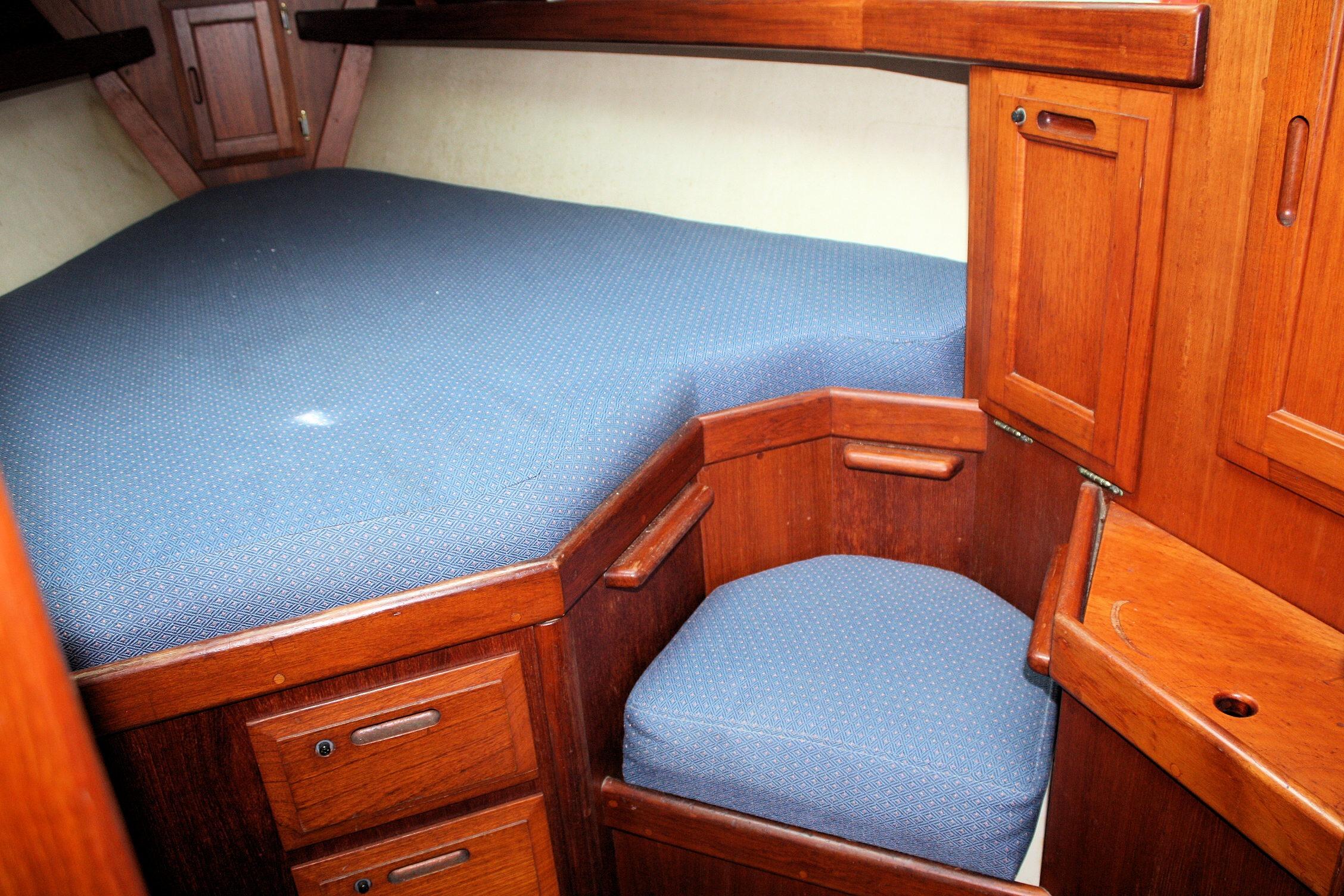 Cozy cabin interior of 1987 Ericson 38-200 sailboat with blue upholstery and wooden cabinetry.