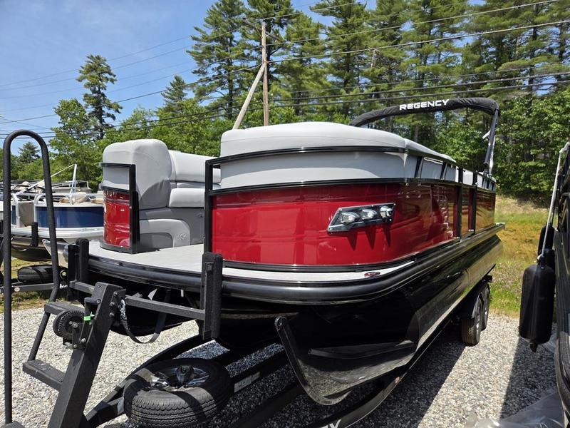 2025 Regency 230 DL3 pontoon boat on trailer, red and gray design, parked outdoors.