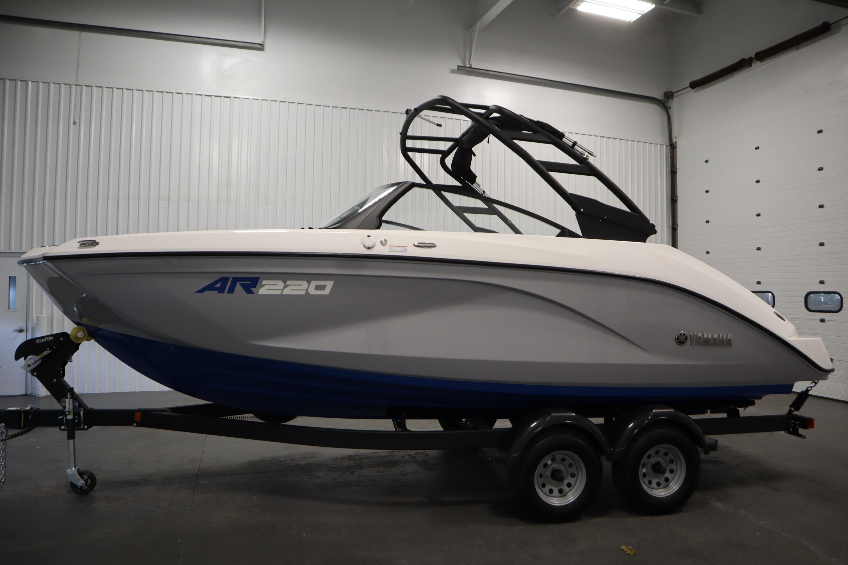 2026 Yamaha Boats AR220 in a showroom, featuring sleek design and dual-axle trailer.