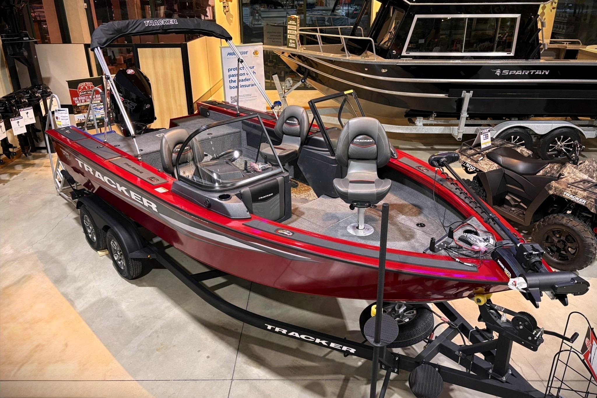 2025 Tracker Targa V-19 WT boat in showroom, featuring sleek red design and modern seating.