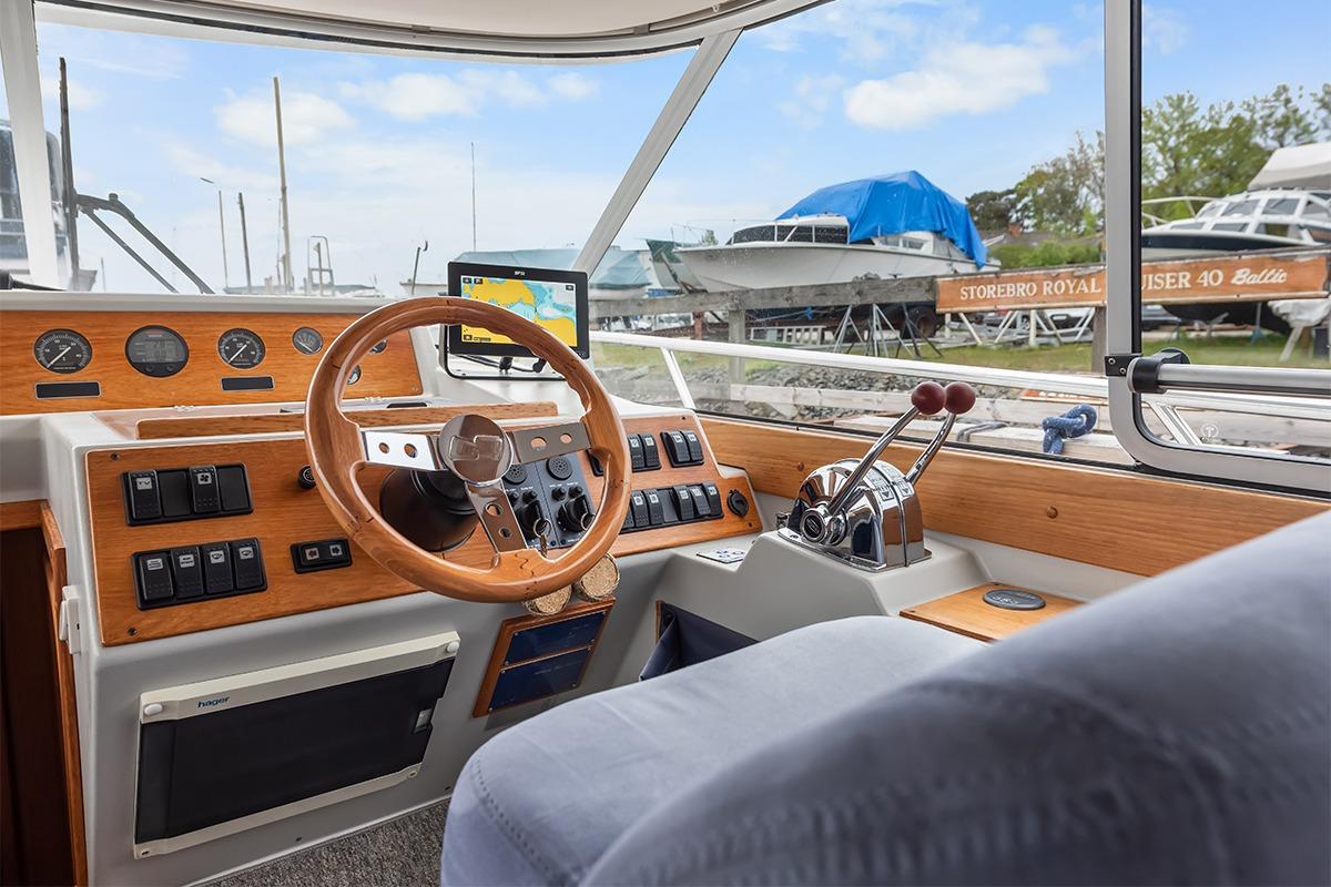 Interior view of 2000 Nimbus 380 Carisma boat cockpit with wooden dashboard and steering wheel.