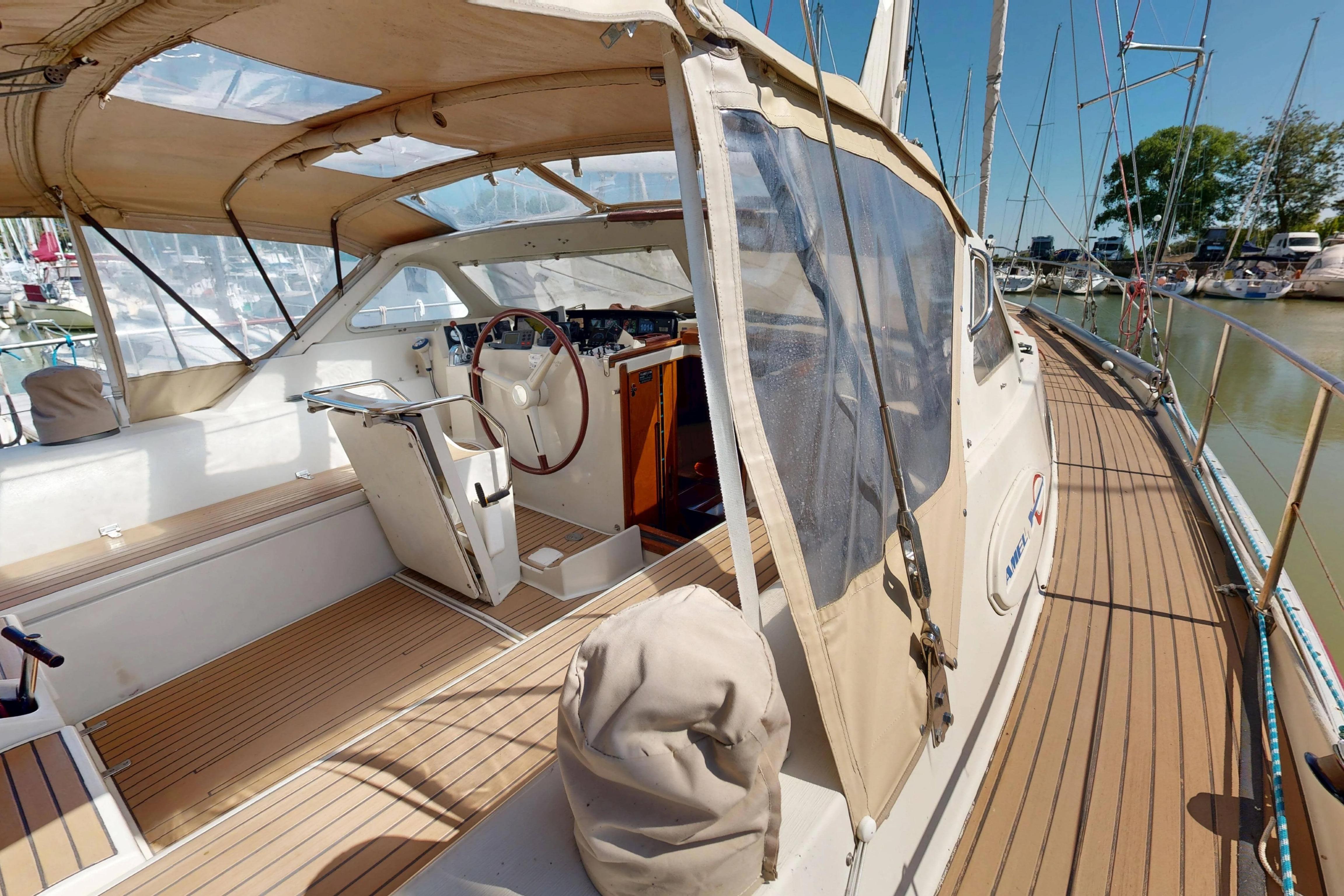 Cockpit view of 1999 Amel Super Maramu 2000 sailboat with wooden deck and canopy.