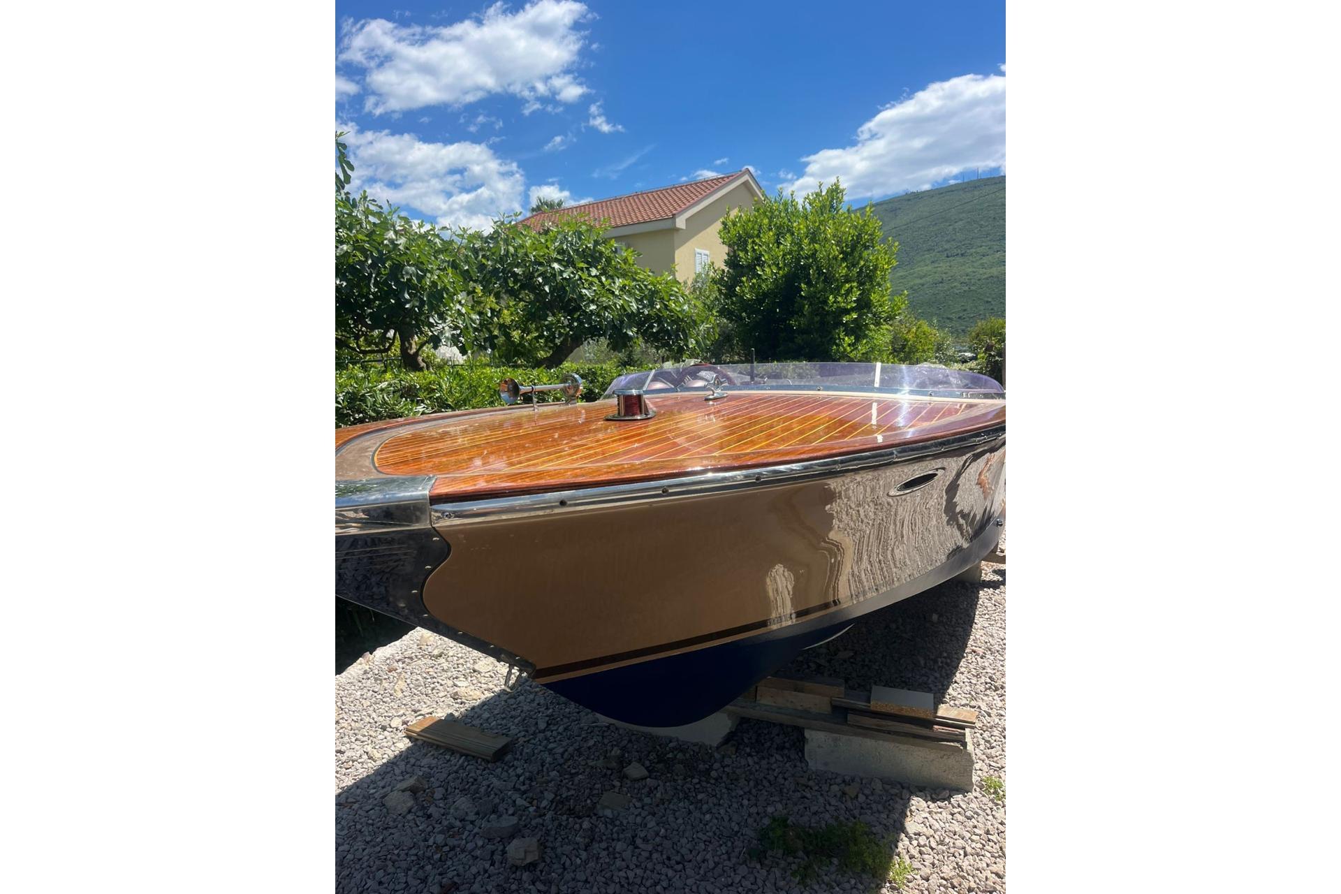 2014 Yuka 580 Speedster boat with wooden deck, parked outdoors under a clear blue sky.