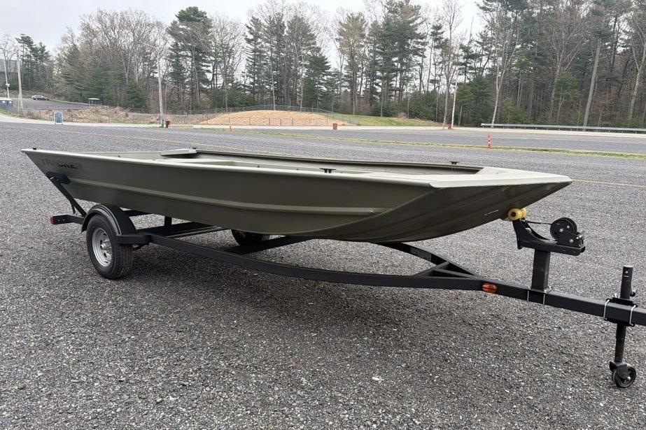 2026 Tracker Grizzly 1754 Utility boat on trailer, parked on gravel with trees in background.