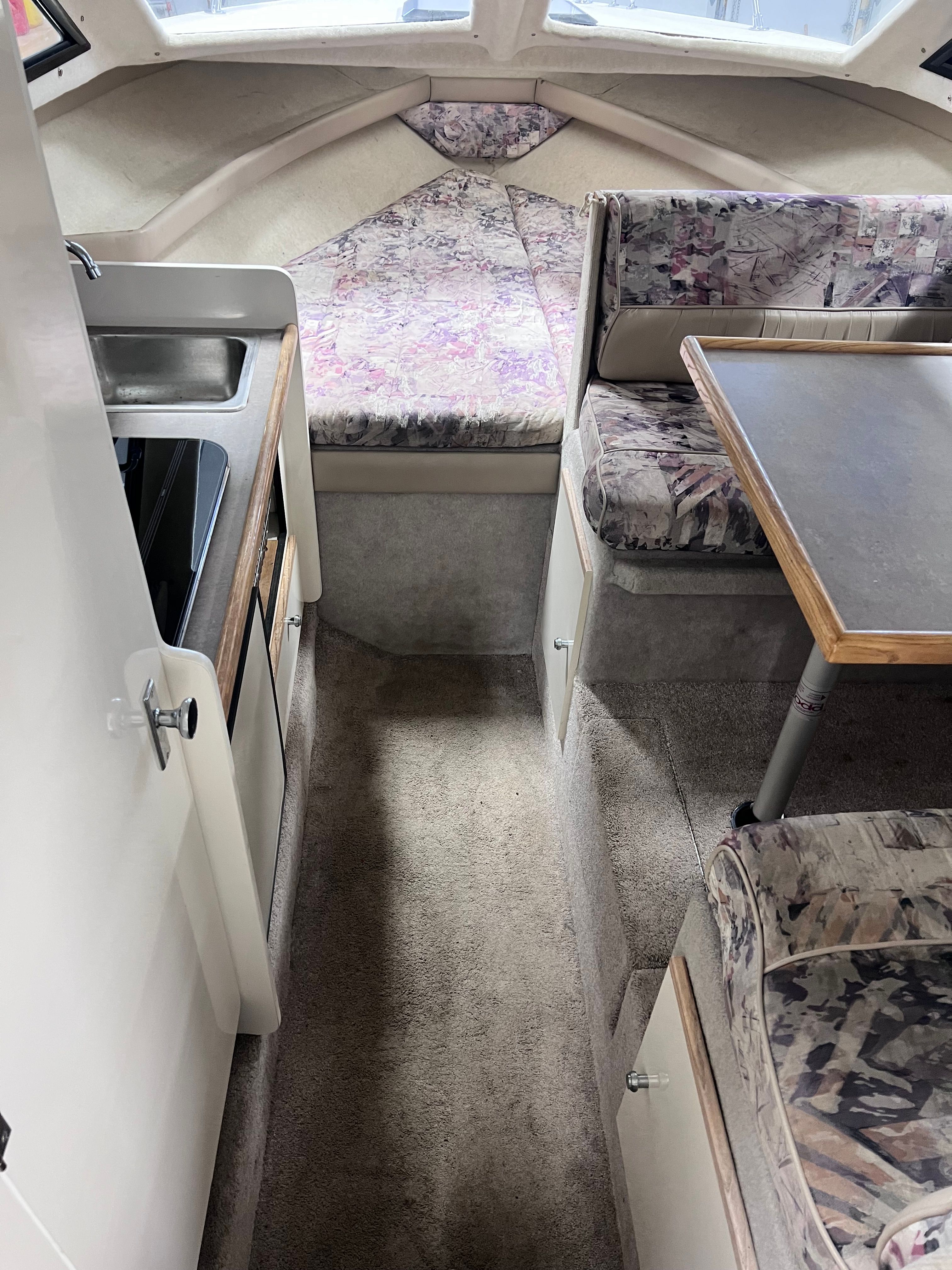 Interior of a 1997 Bayliner 2452 with kitchenette and seating area.