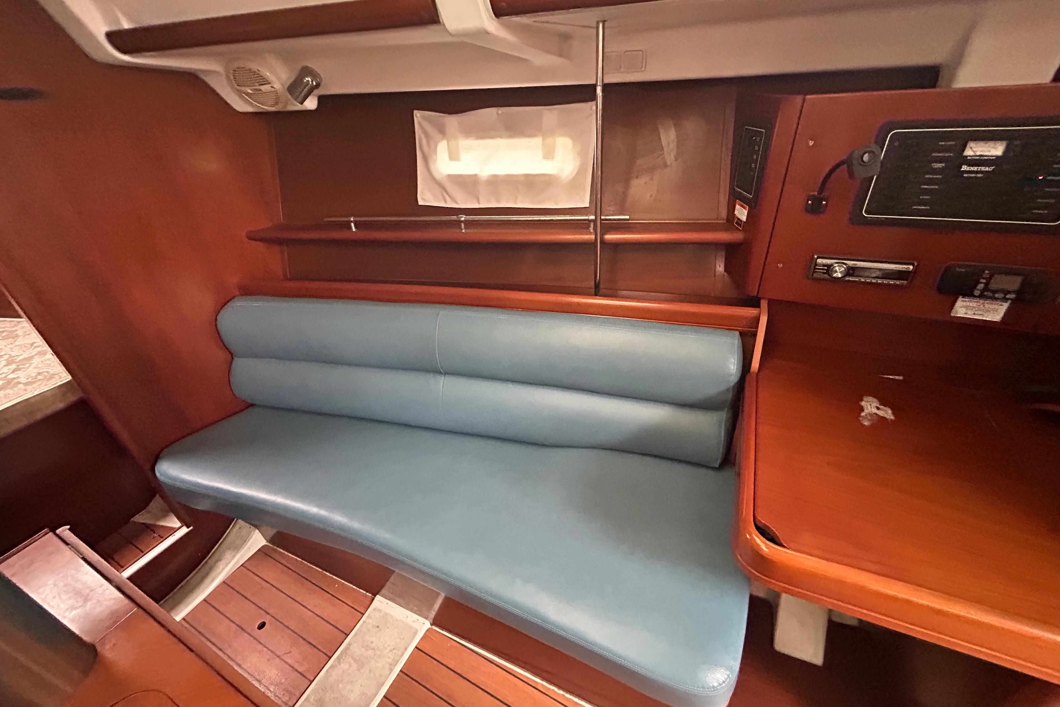 2006 Beneteau 343 yacht interior with blue seating and wooden cabinetry.