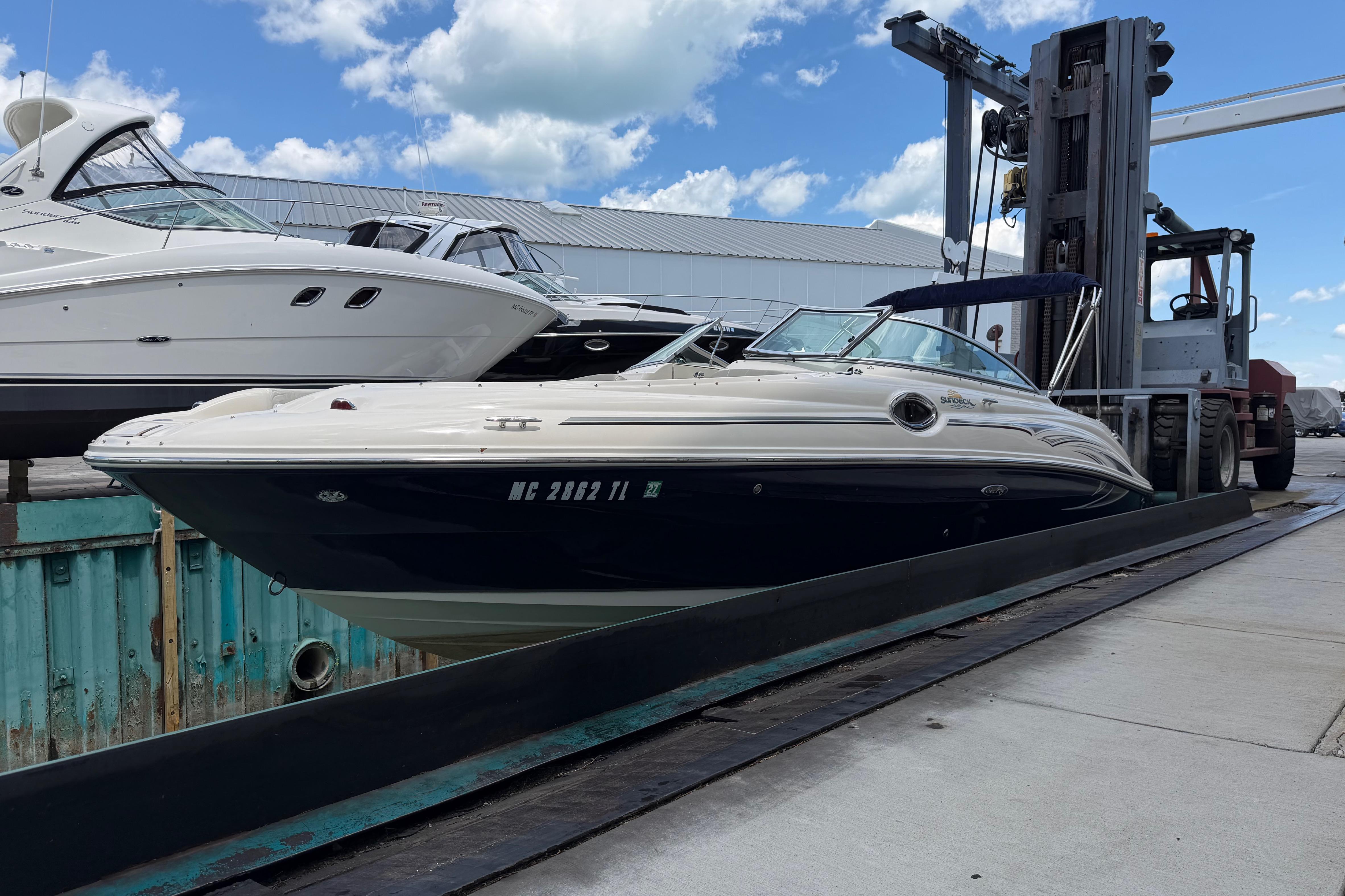 2004 Sea Ray 240 Sundeck boat on a lift at a marina under a blue sky.