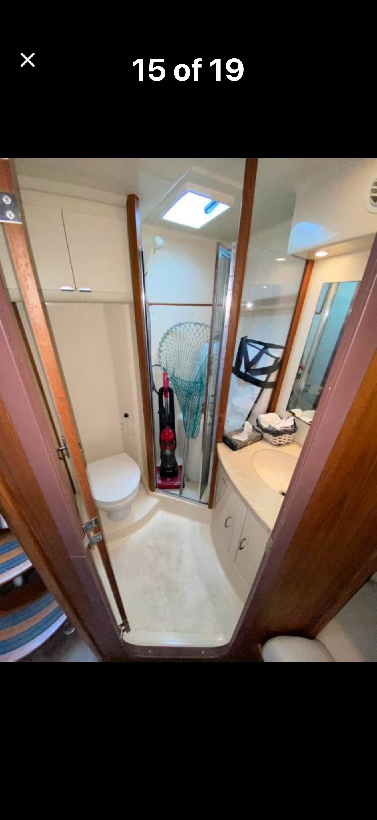 Interior view of a boat bathroom with toilet, sink, and storage.